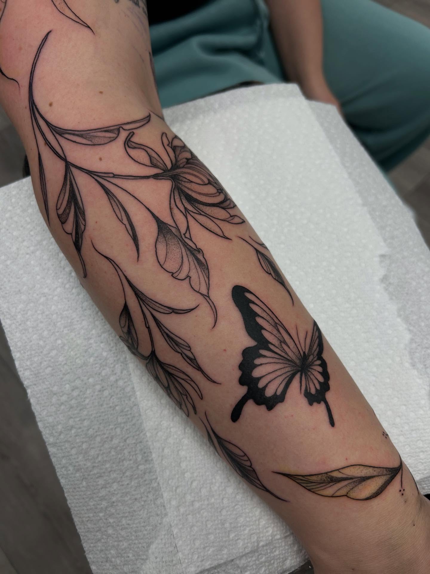 Butterfly and floral black and grey tattoo on the forearm by Livy baby