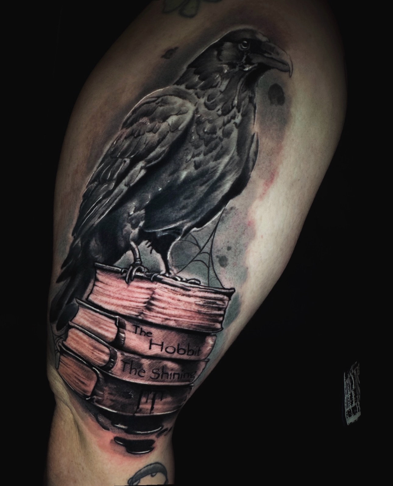 Crow perched on books realism tattoo on the forearm by Donald Reynolds