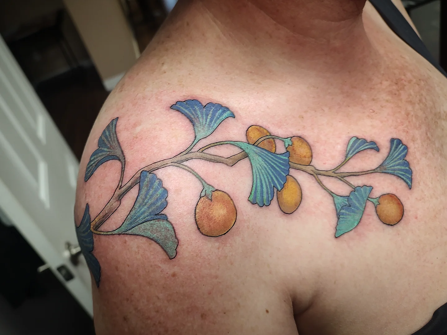 Gingko leaves and nuts realism tattoo on the shoulder by Jennifer Fowler