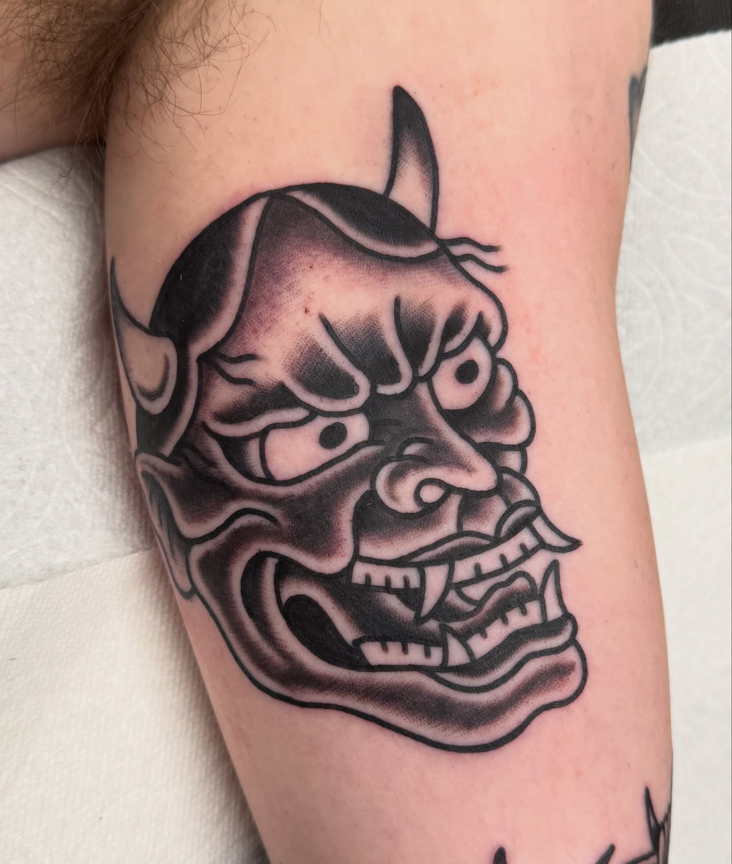 Demon mask black and grey tattoo on the forearm by Joey Burdette Tattoos