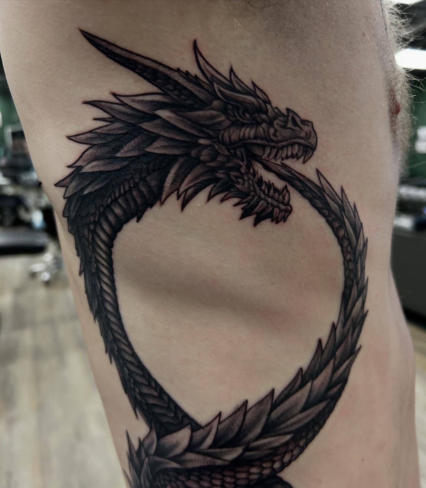 Dragon black and grey tattoo on the thigh by Mayhem Andrews