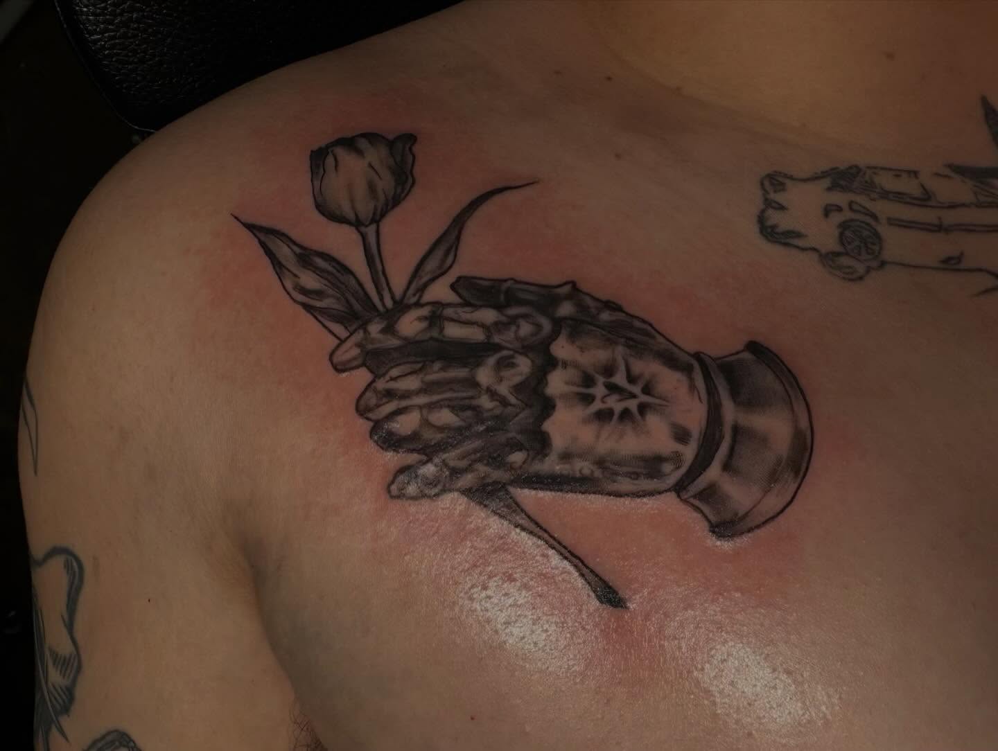 Hand holding tulip black and grey tattoo on the shoulder by ★𝐑𝐮𝐞★