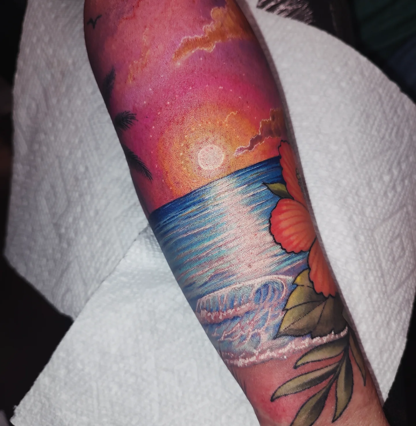 Sunset over ocean watercolor tattoo on the forearm by Jennifer Fowler