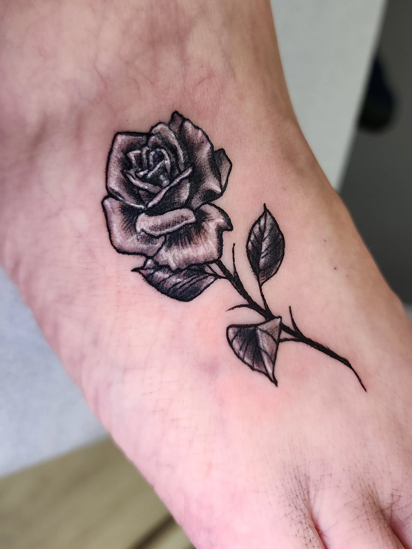 Rose black and grey tattoo on the forearm by Zach Mullins