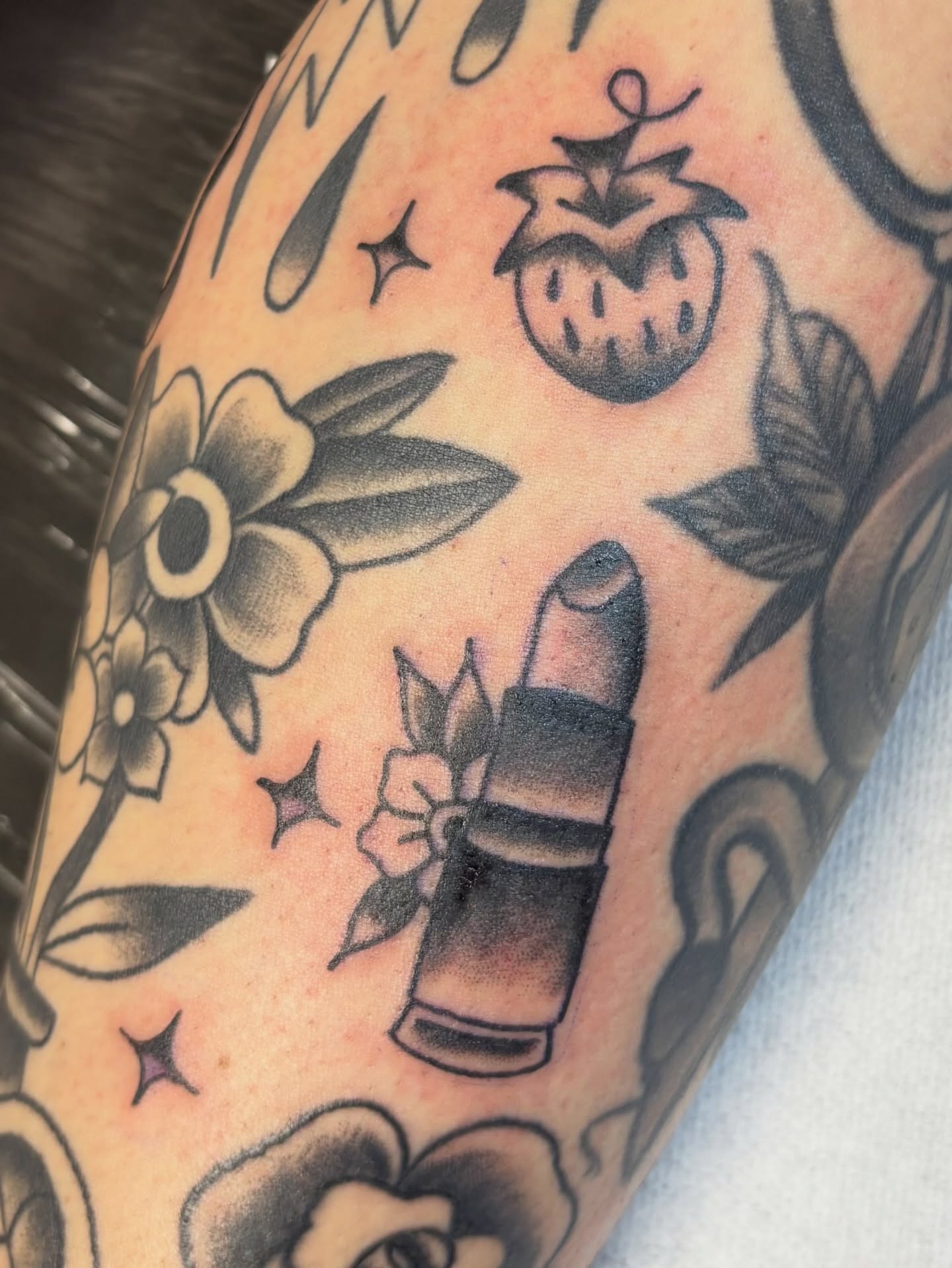 Lipstick and flowers American traditional tattoo on the forearm by Bridget Smith