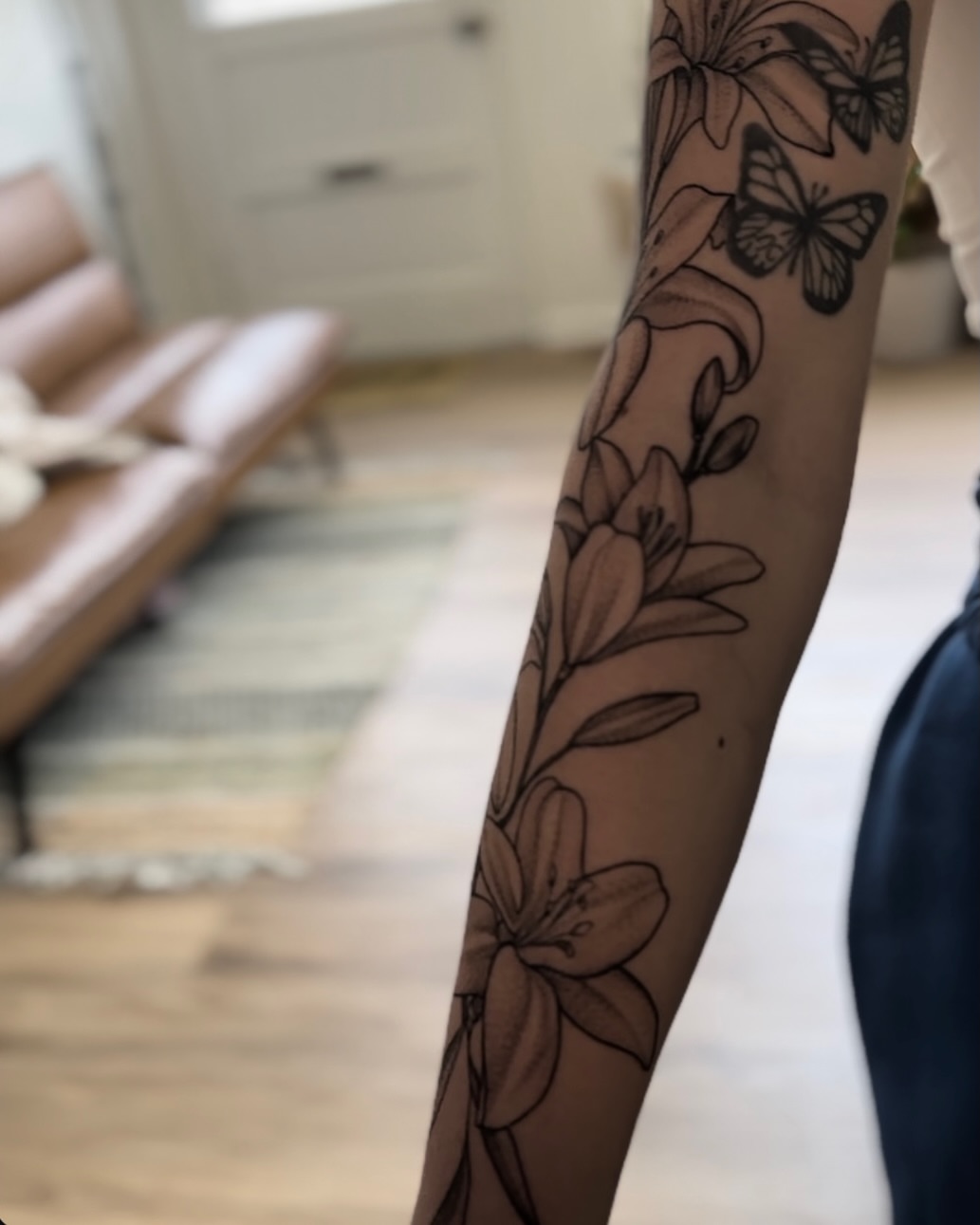 Lilies and butterflies black and grey tattoo on the forearm by Allexis