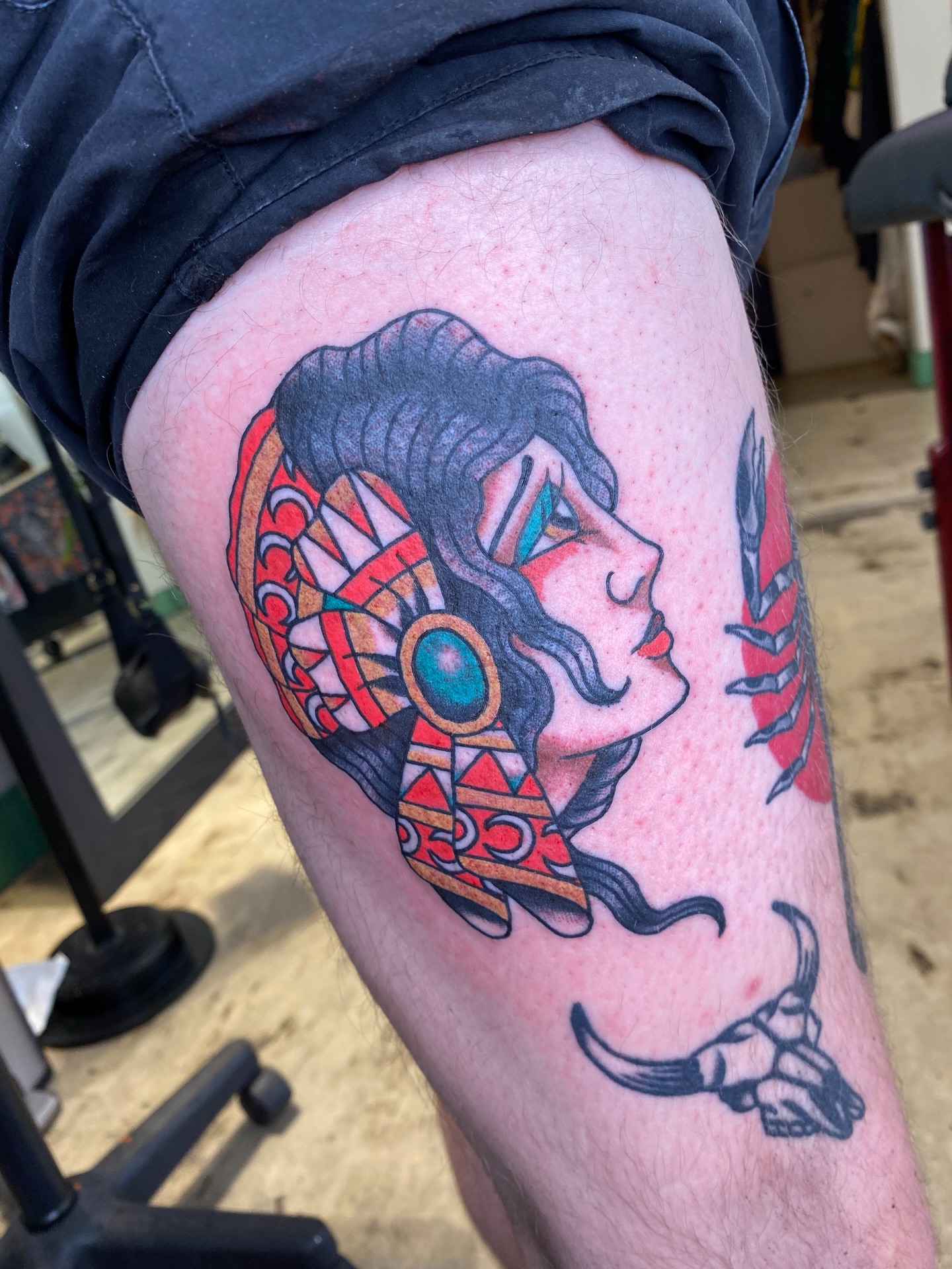 Woman with headdress American traditional tattoo on the thigh by Mike "Yogi" Trube