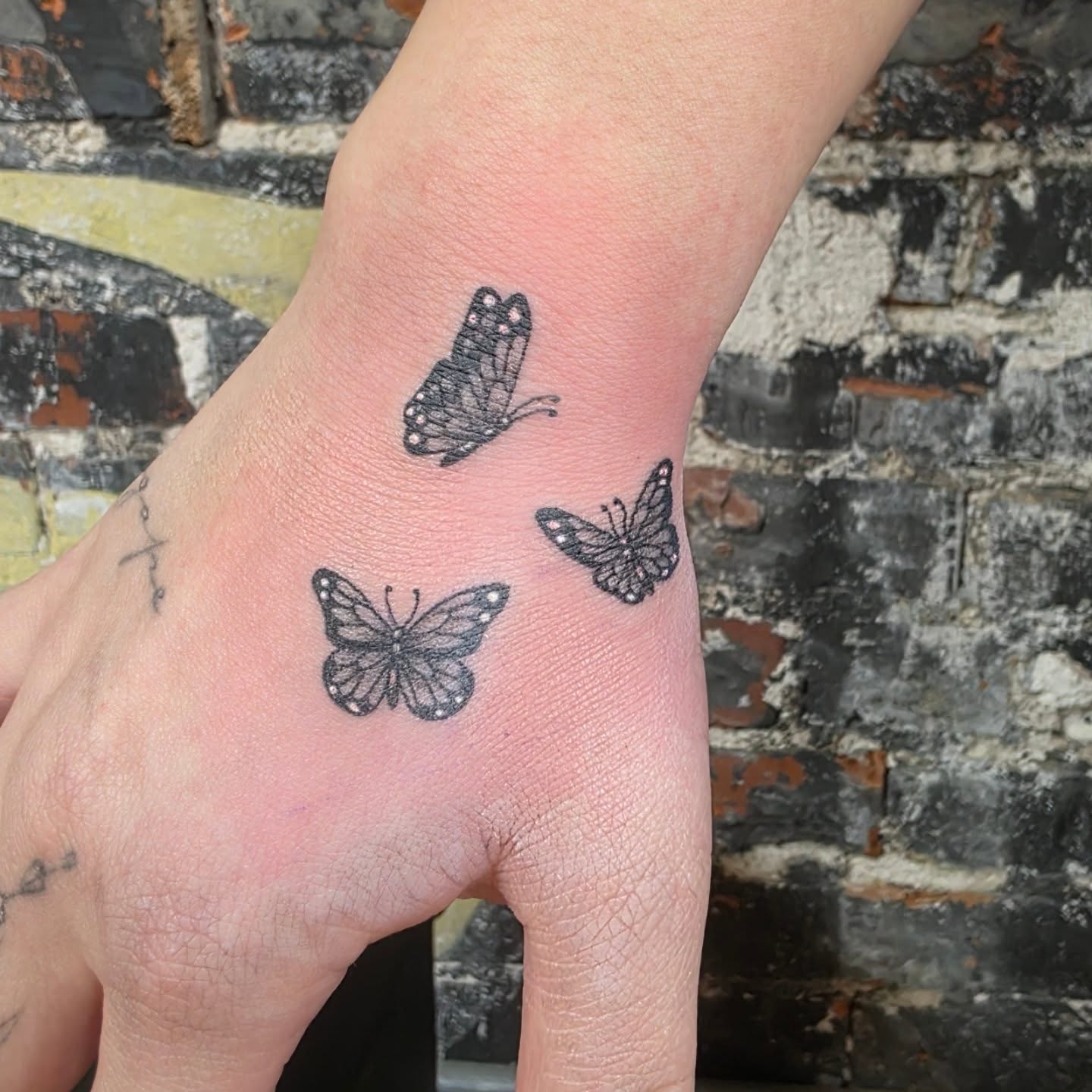 Butterflies black and grey tattoo on the hand by Tattoos by Annie