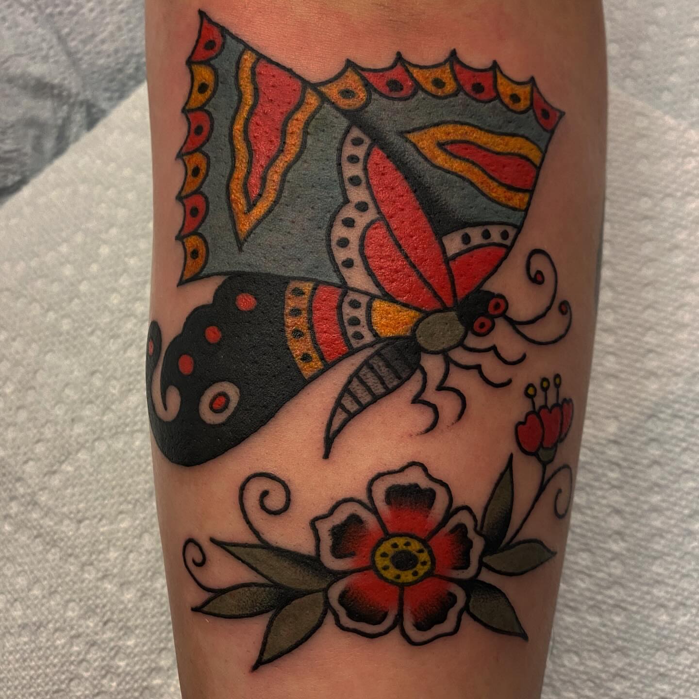 Butterfly and flowers American traditional tattoo on the forearm by Abby Rose Estes