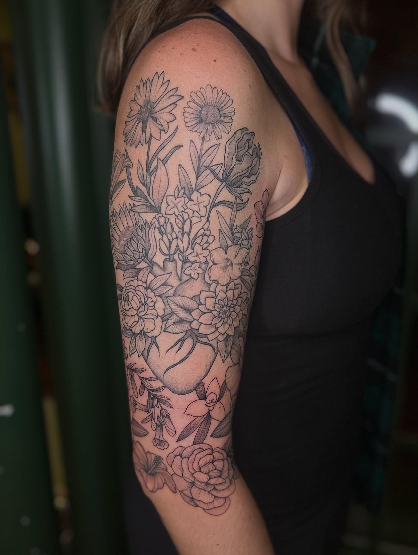 Floral bouquet black and grey tattoo on the upper arm by Brieana Smith