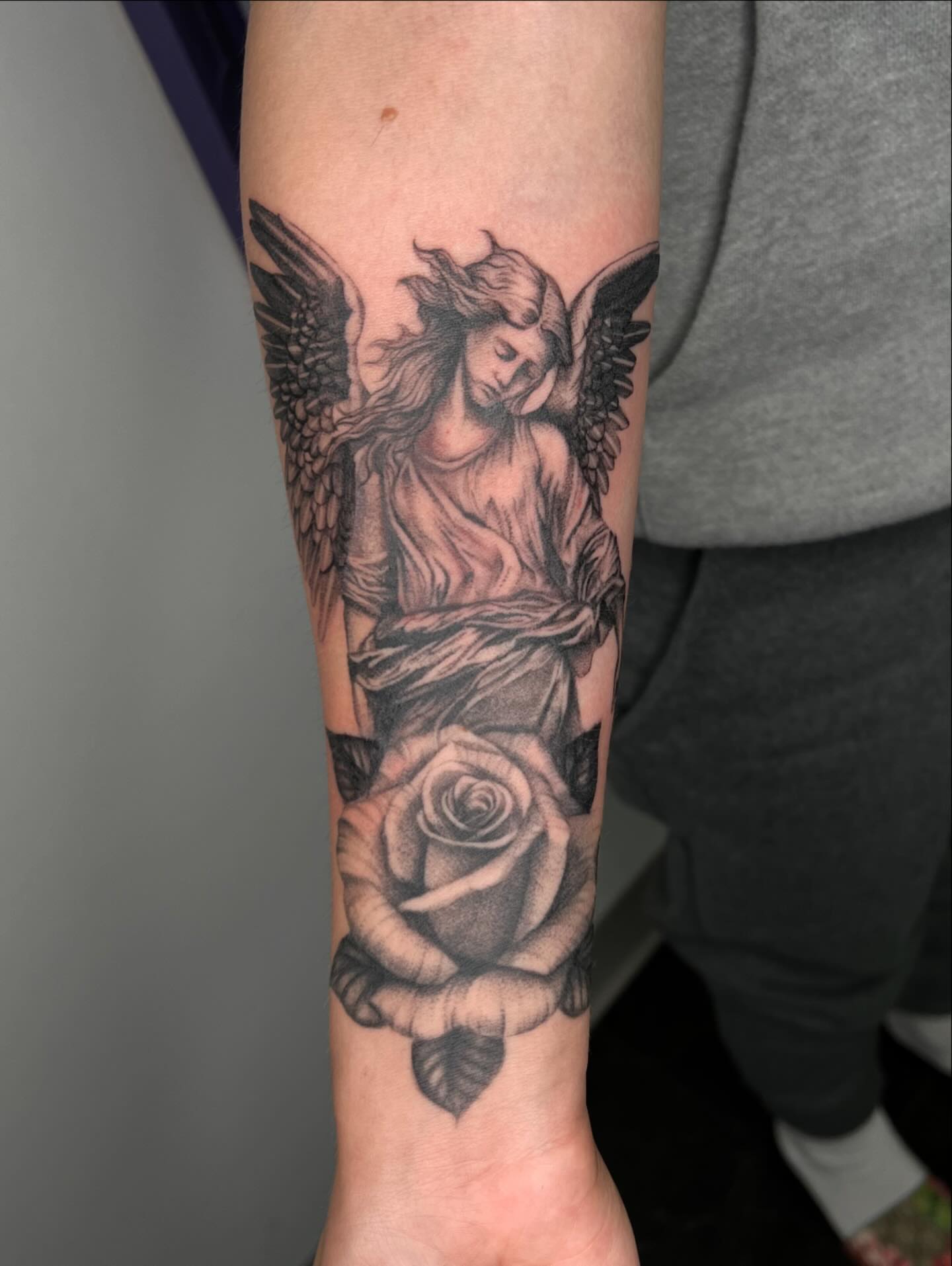 Angel with rose realism tattoo on the forearm by San Diego Fineline Black & Grey Tattoo Artist