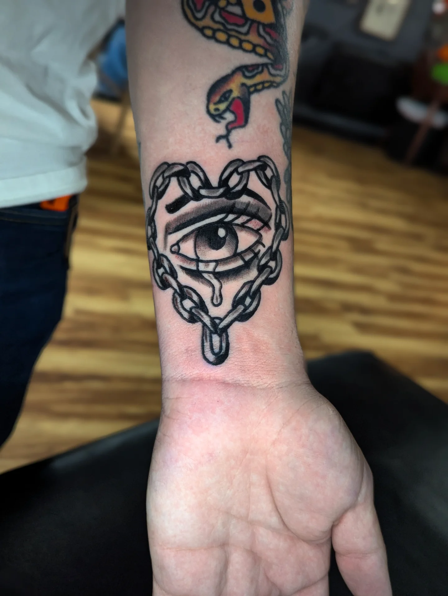 Eye with chains black and grey tattoo on the forearm by Eric Ward