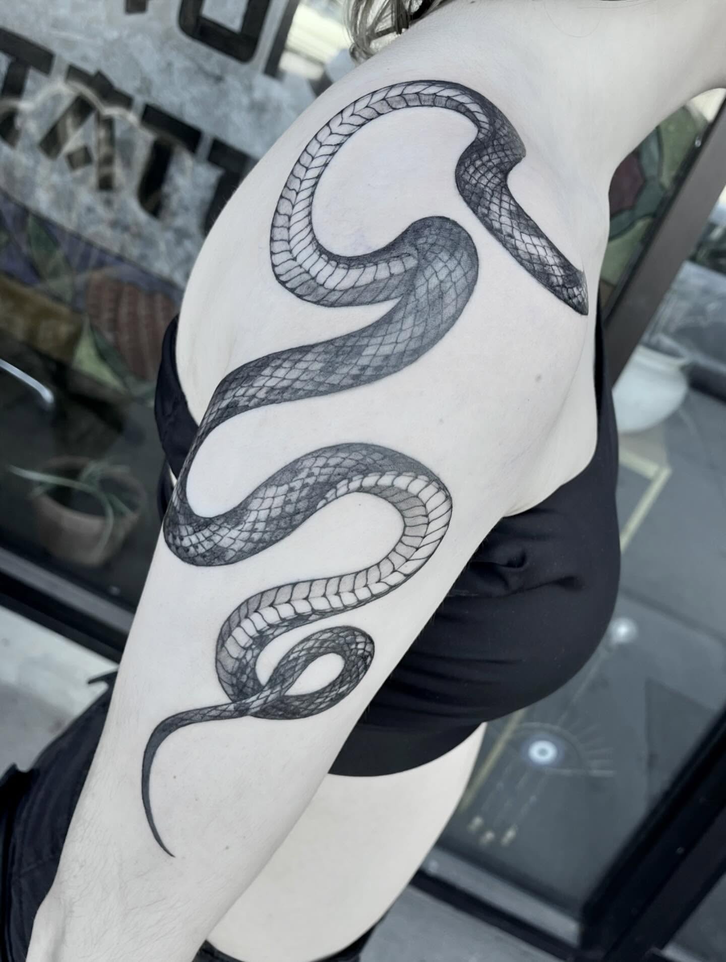 Snake black and grey tattoo on the upper arm by Nathan Esteras