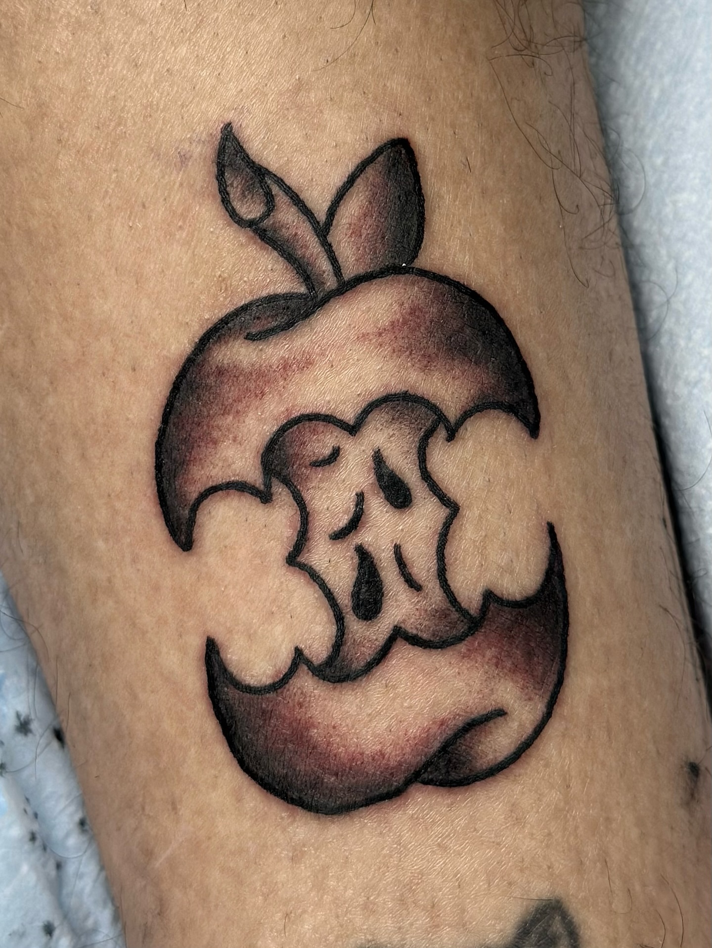 Poisoned apple black and grey tattoo on the forearm by Lucy Jay