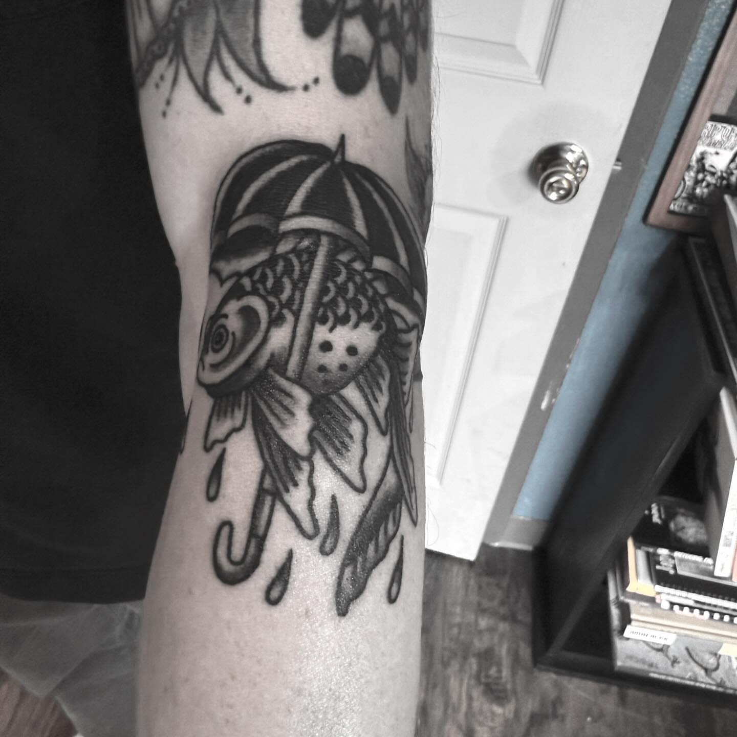 Umbrella and fish black and grey tattoo on the forearm by Joe Truck