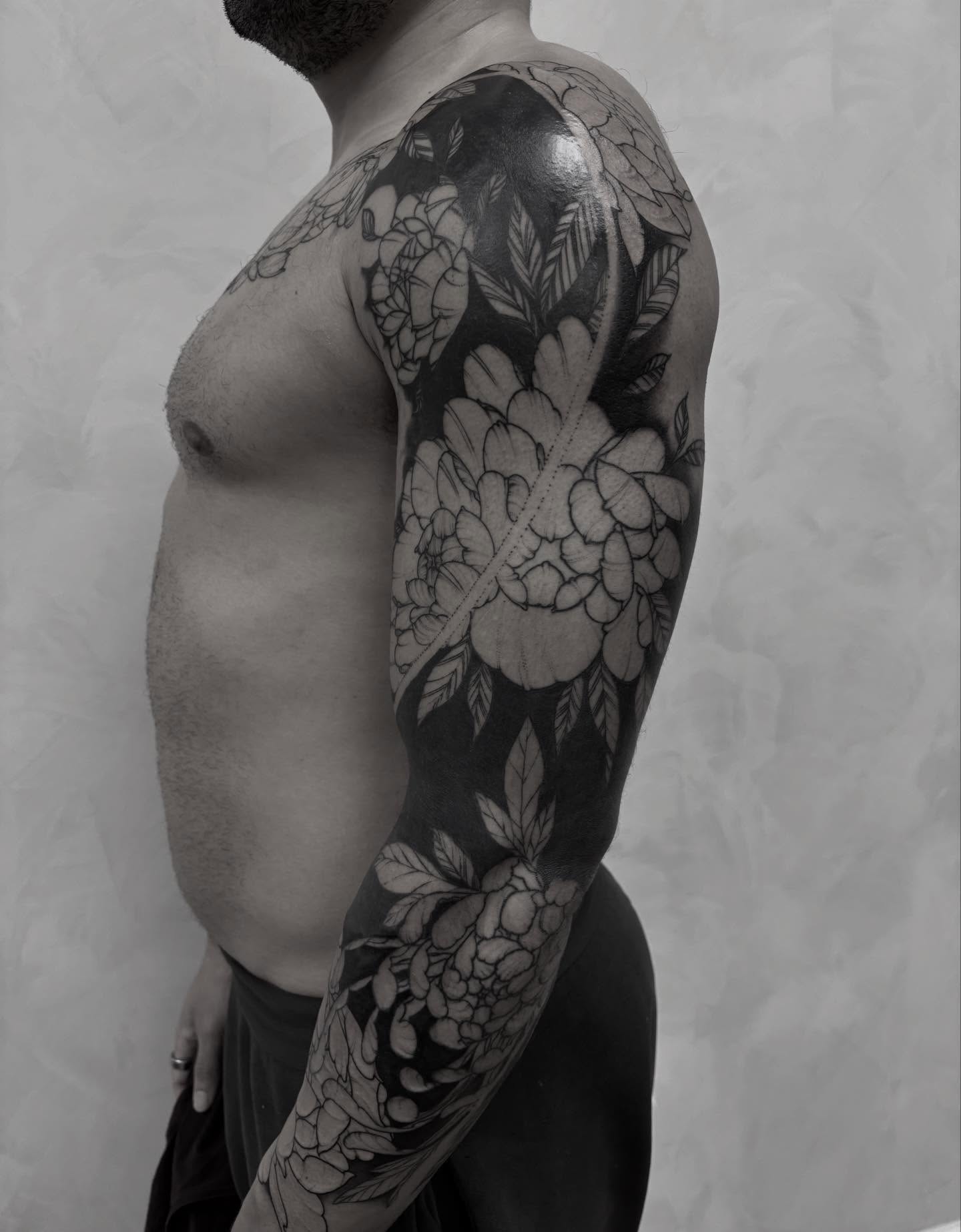 Floral black and grey tattoo on the upper arm by Dallas Davis