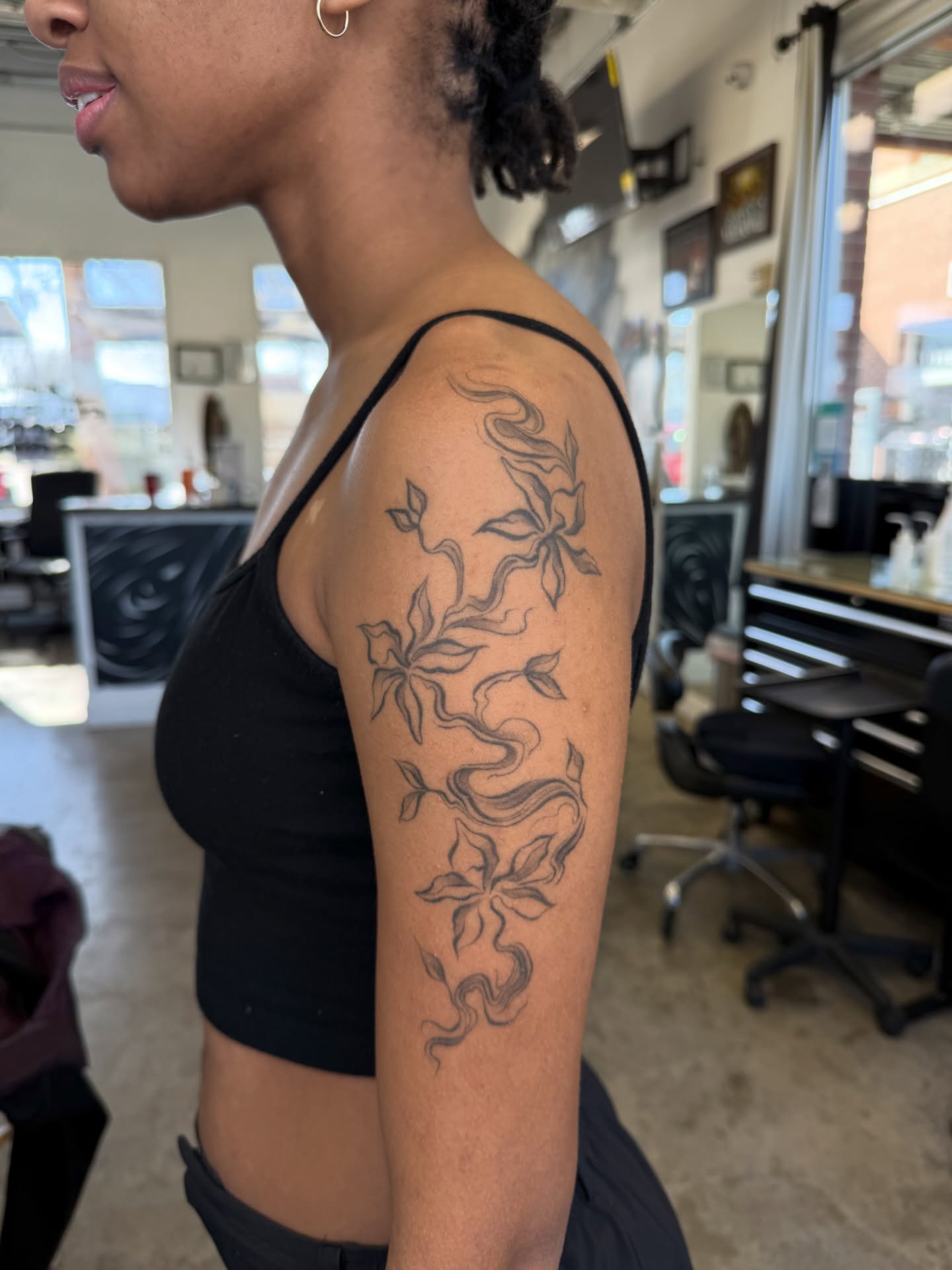 Floral design black and grey tattoo on the upper arm by Ricky Sanchez, Duncanville, Texas