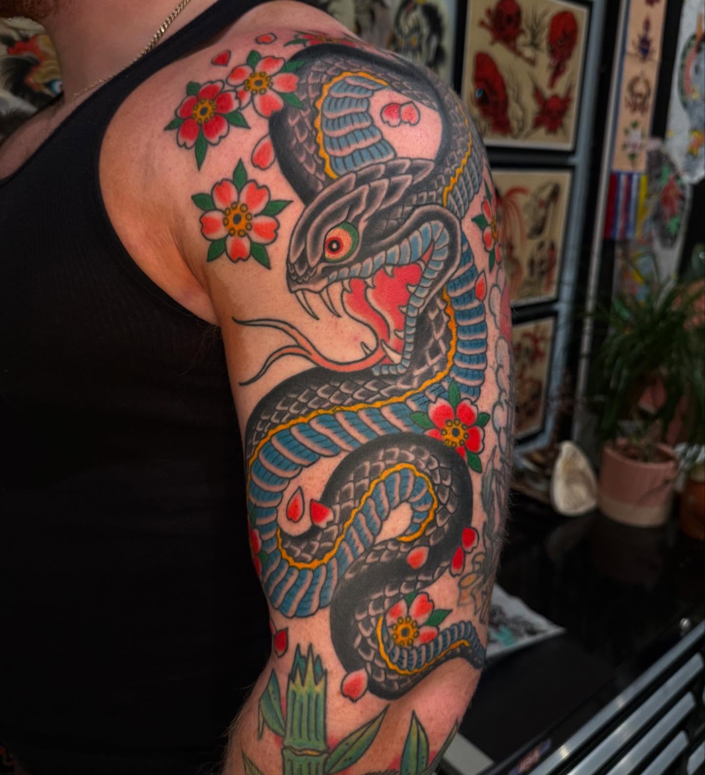 Snake and flowers American traditional tattoo on the forearm by Noah Moretz