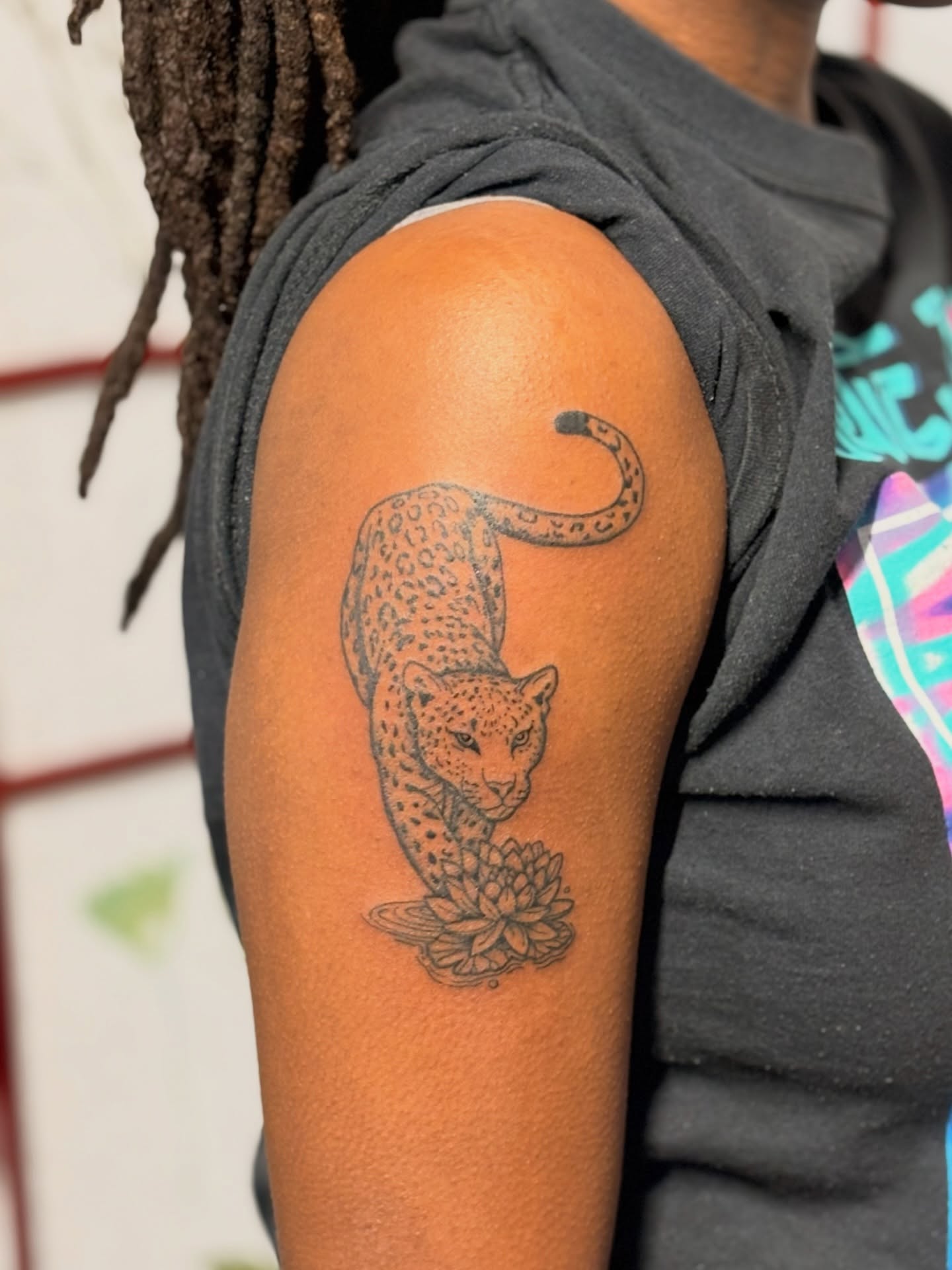 Leopard and lotus black and grey tattoo on the upper arm by CJ