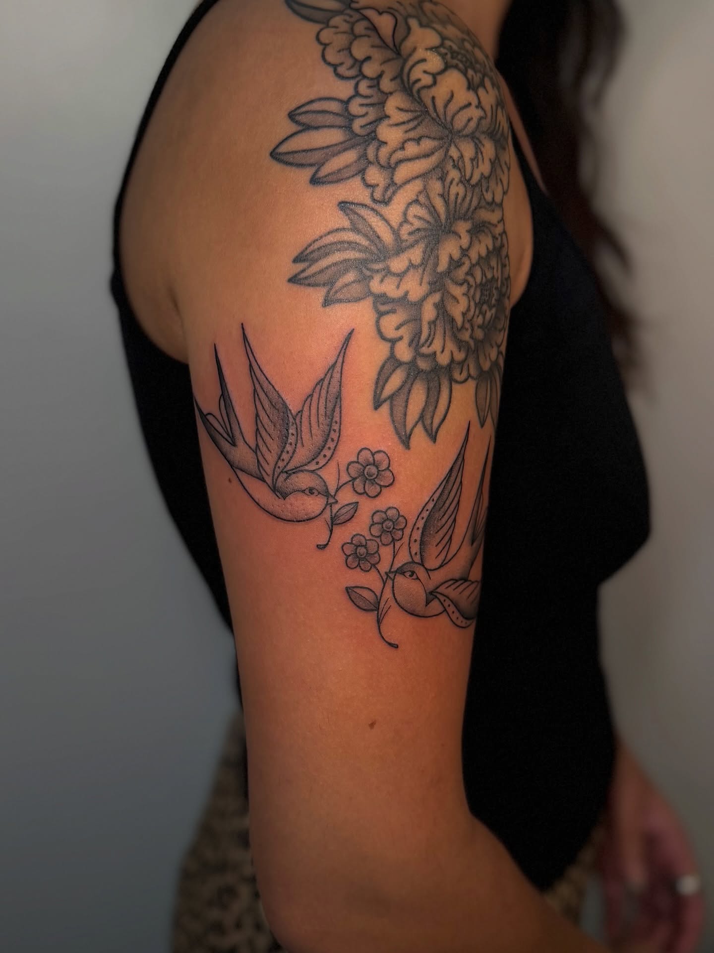 Birds and flowers black and grey tattoo on the upper arm by Kail