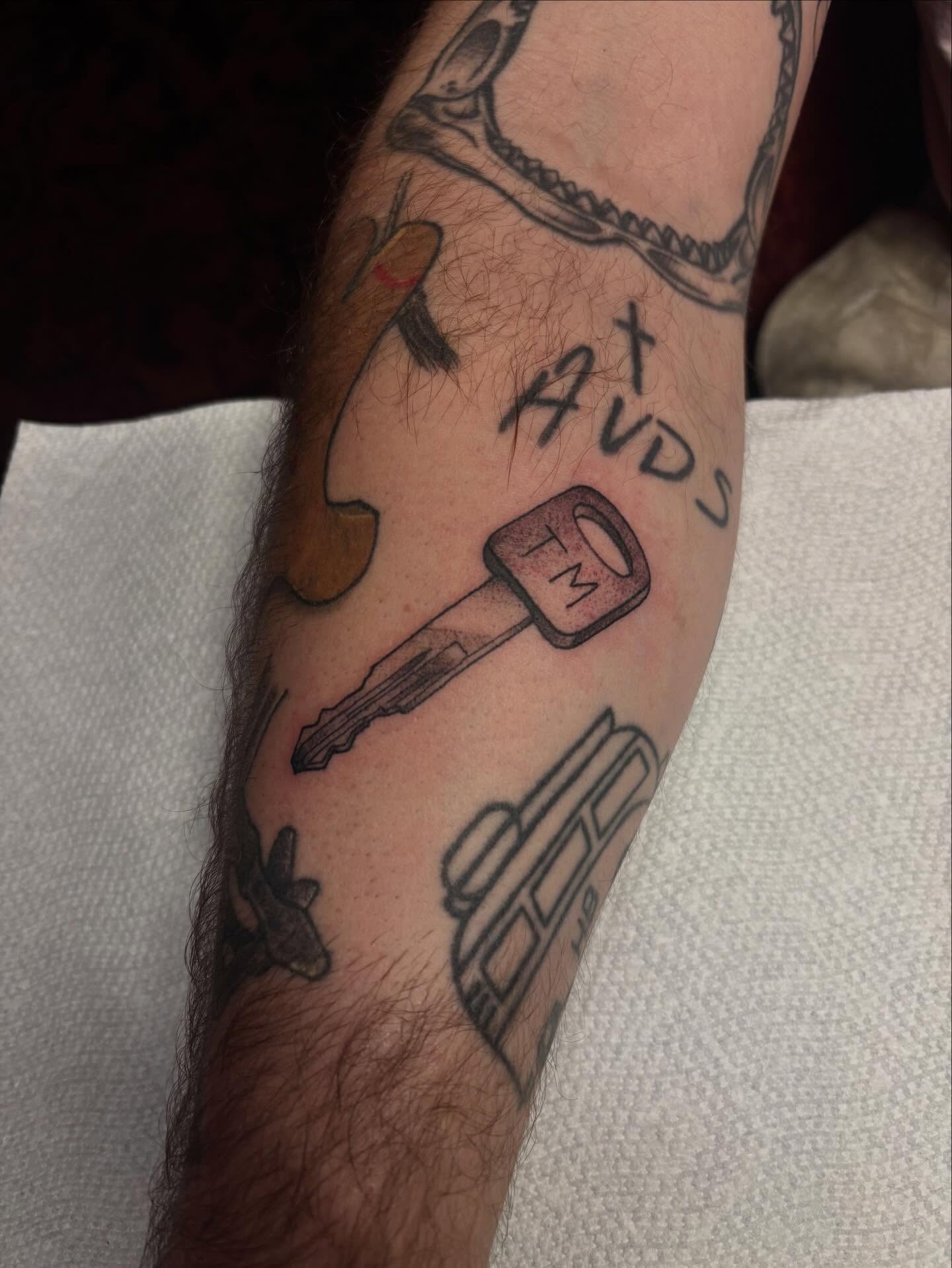Key and car black and grey tattoo on the forearm by Dyllan Shipley