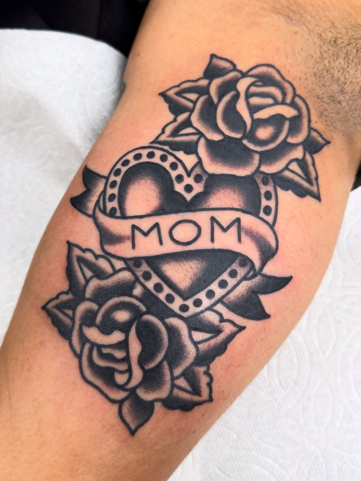 Heart with roses American traditional tattoo on the forearm by Joey Burdette Tattoos