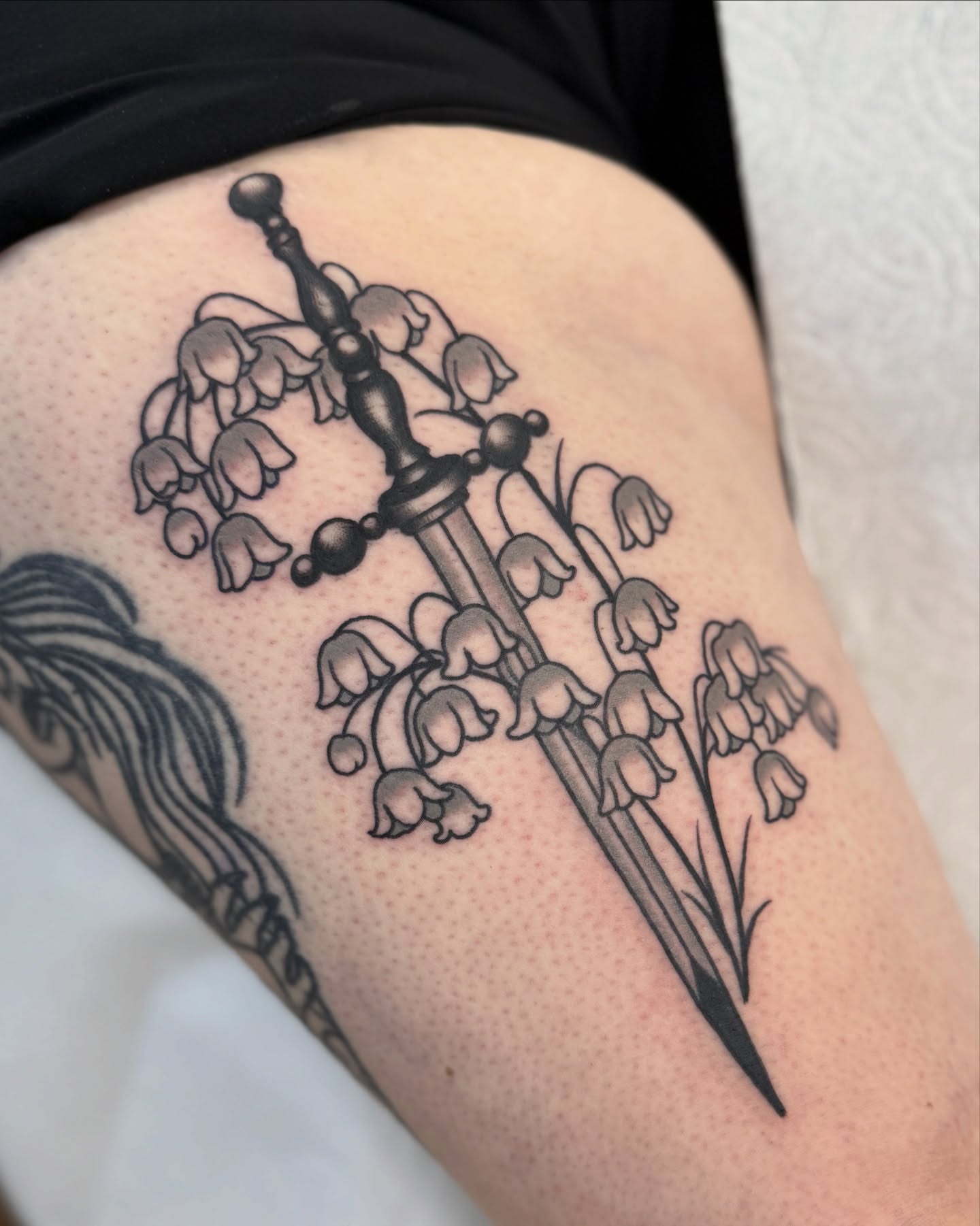 Lily of the valley black and grey tattoo on the thigh by Nia (Knee-uhh) 🦷