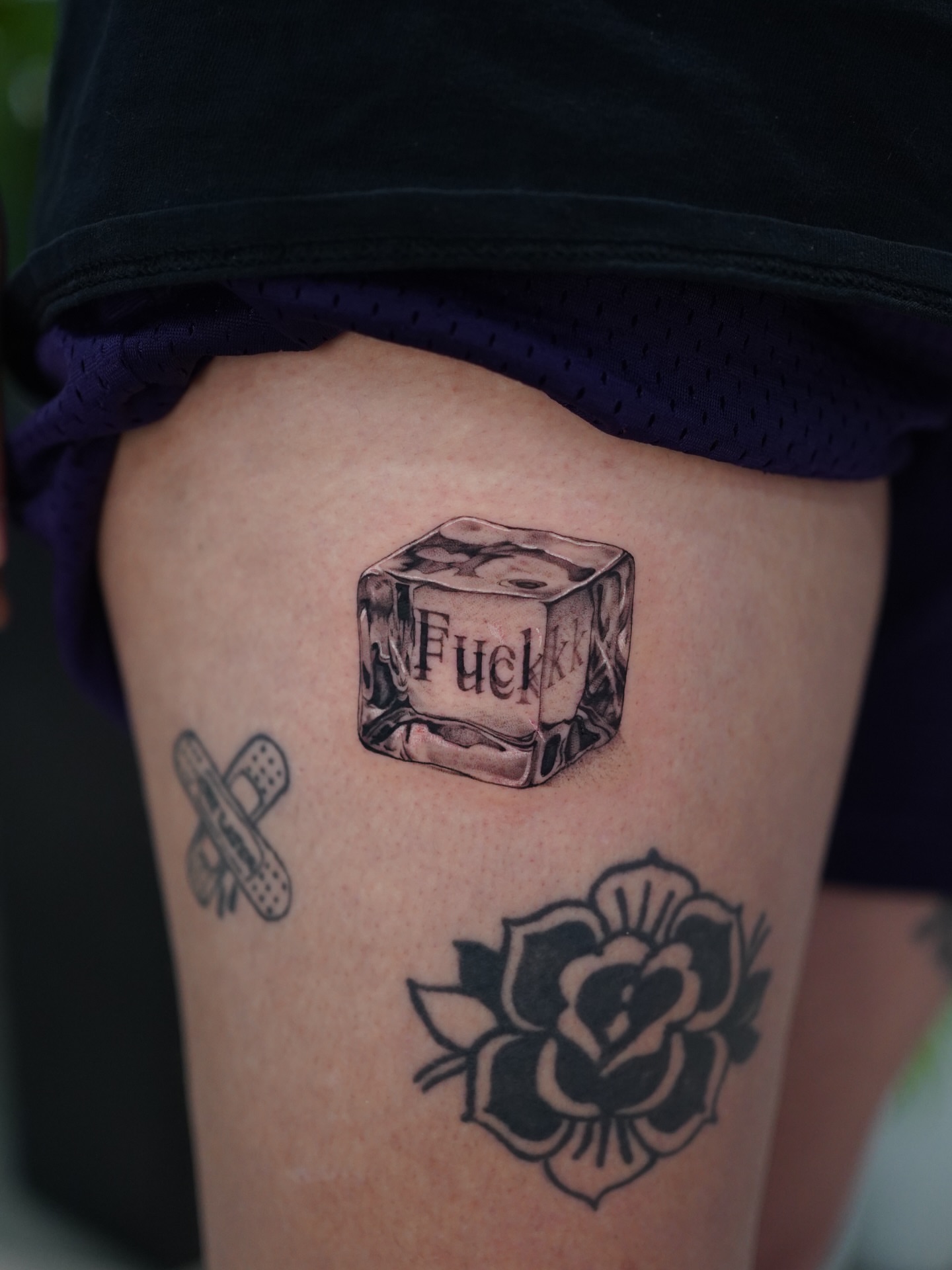Ice cube with text realism tattoo on the thigh by Jess Dominguez