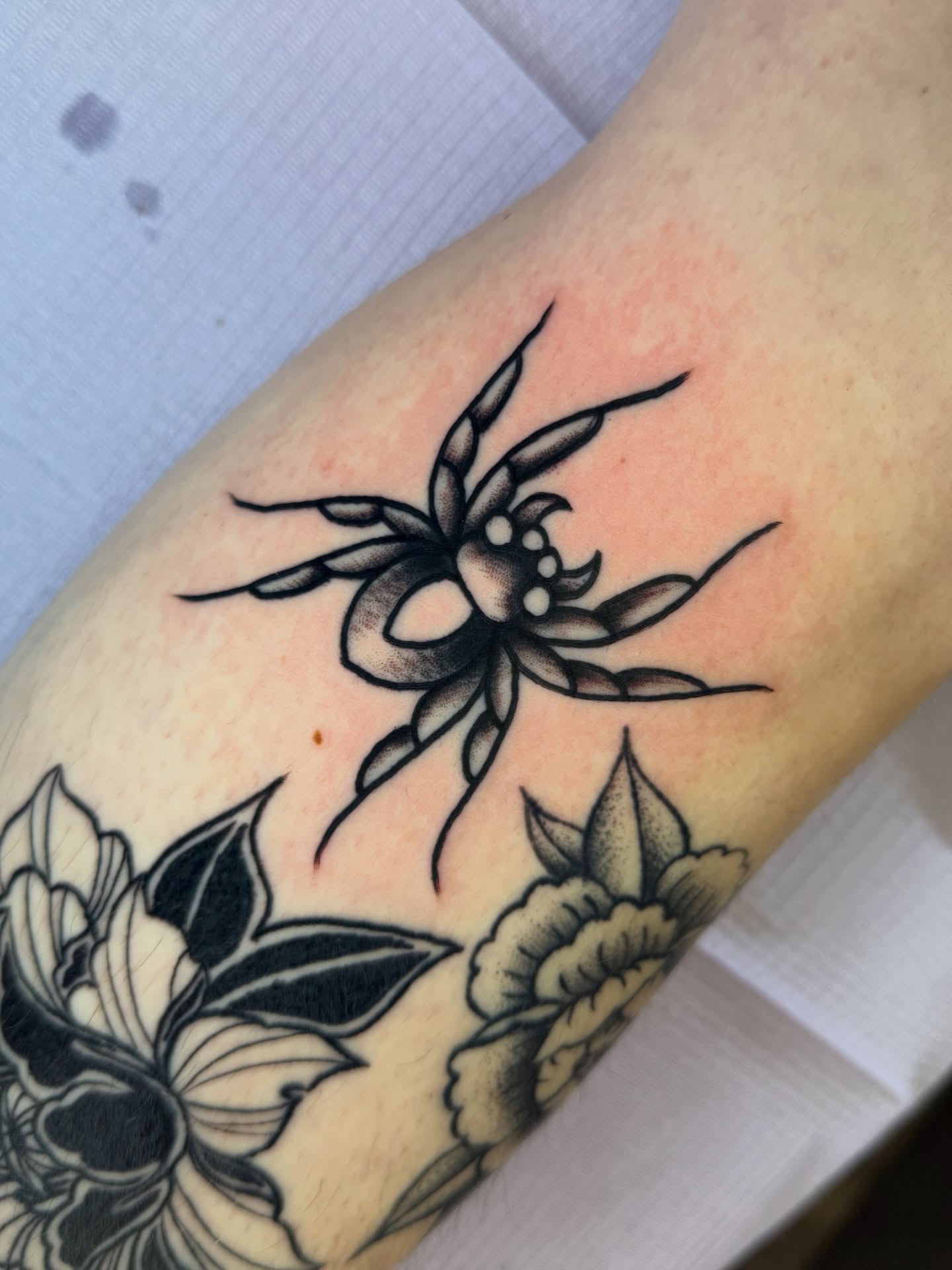 Spider and flowers black and grey tattoo on the forearm by @ryanpereztattoo
