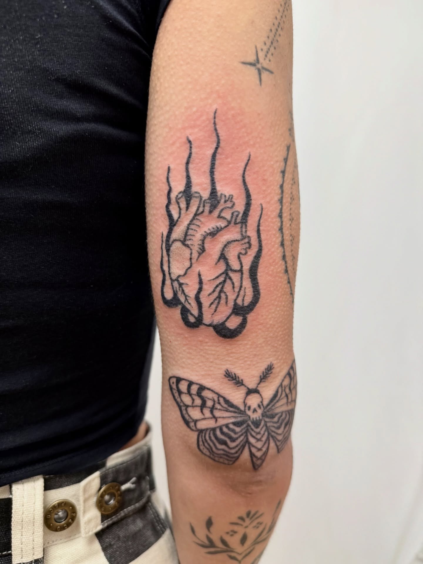 Heart and moth black and grey tattoo on the forearm by Melia Mariko