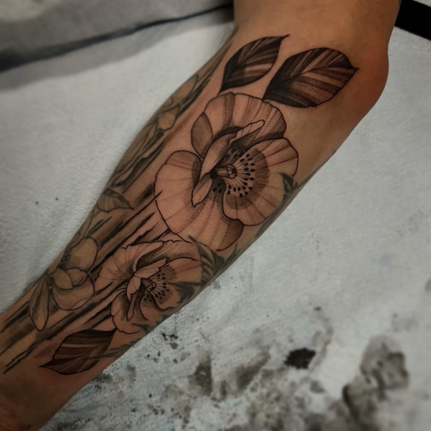 Floral bouquet black and grey tattoo on the forearm by Sebastian Livingston