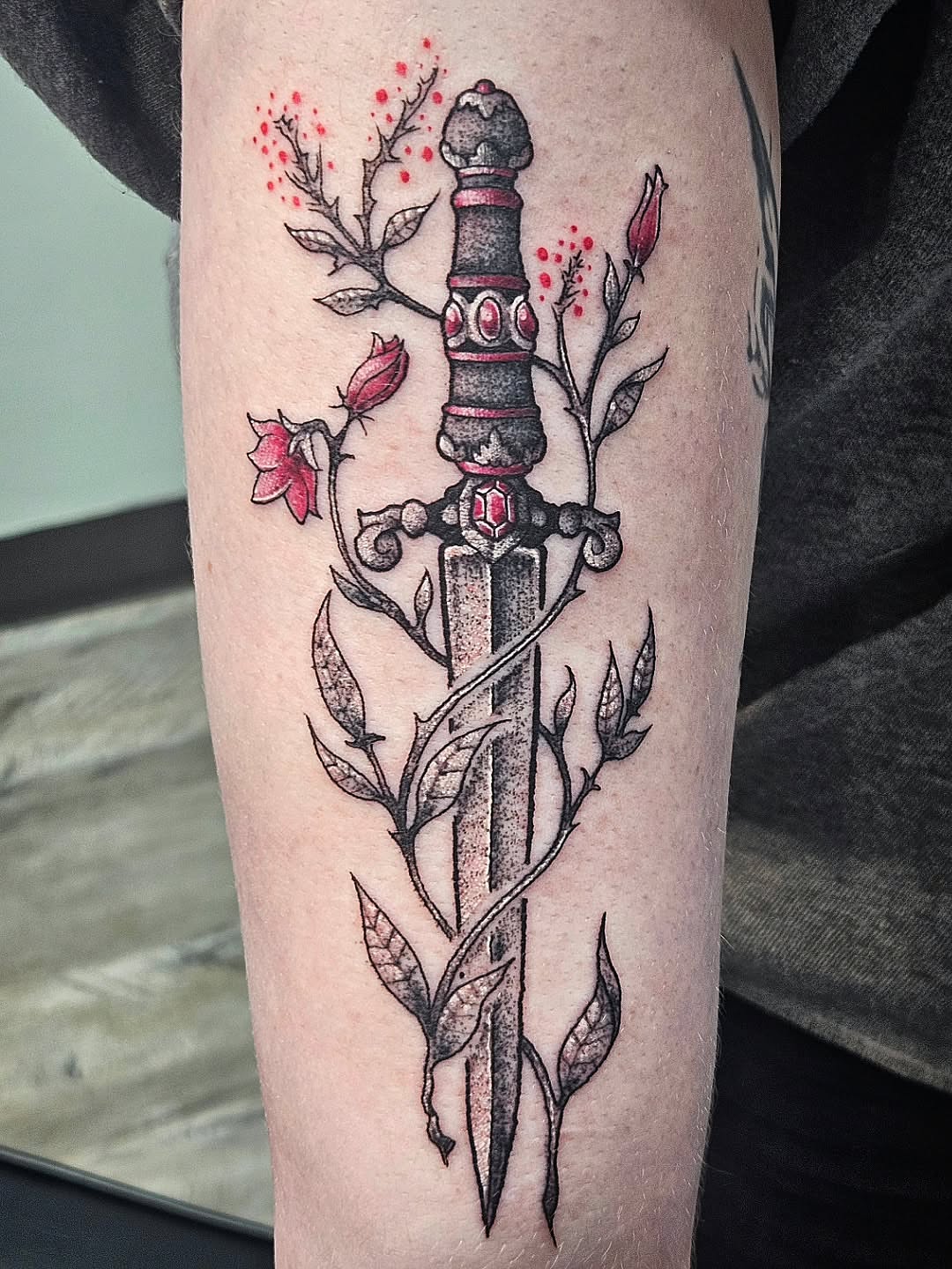 Sword and flowers ornamental tattoo on the forearm by Damian Eames