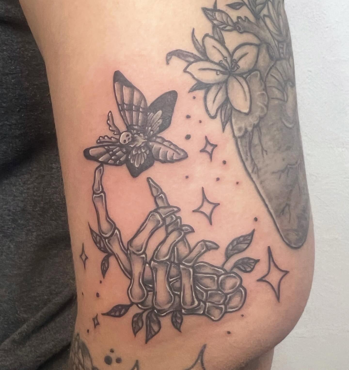 Butterfly and bones black and grey tattoo on the forearm by Amber Rose