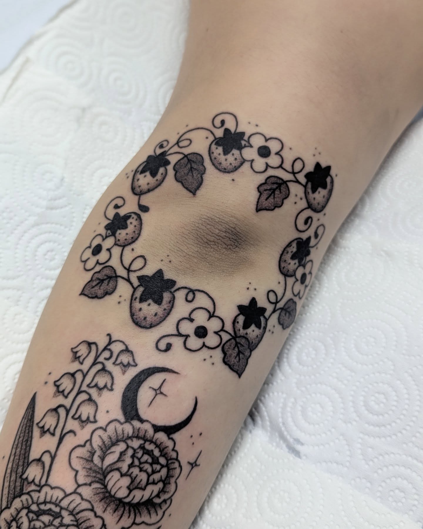 Botanical and celestial motifs black and grey tattoo on the forearm by Dani Harkey