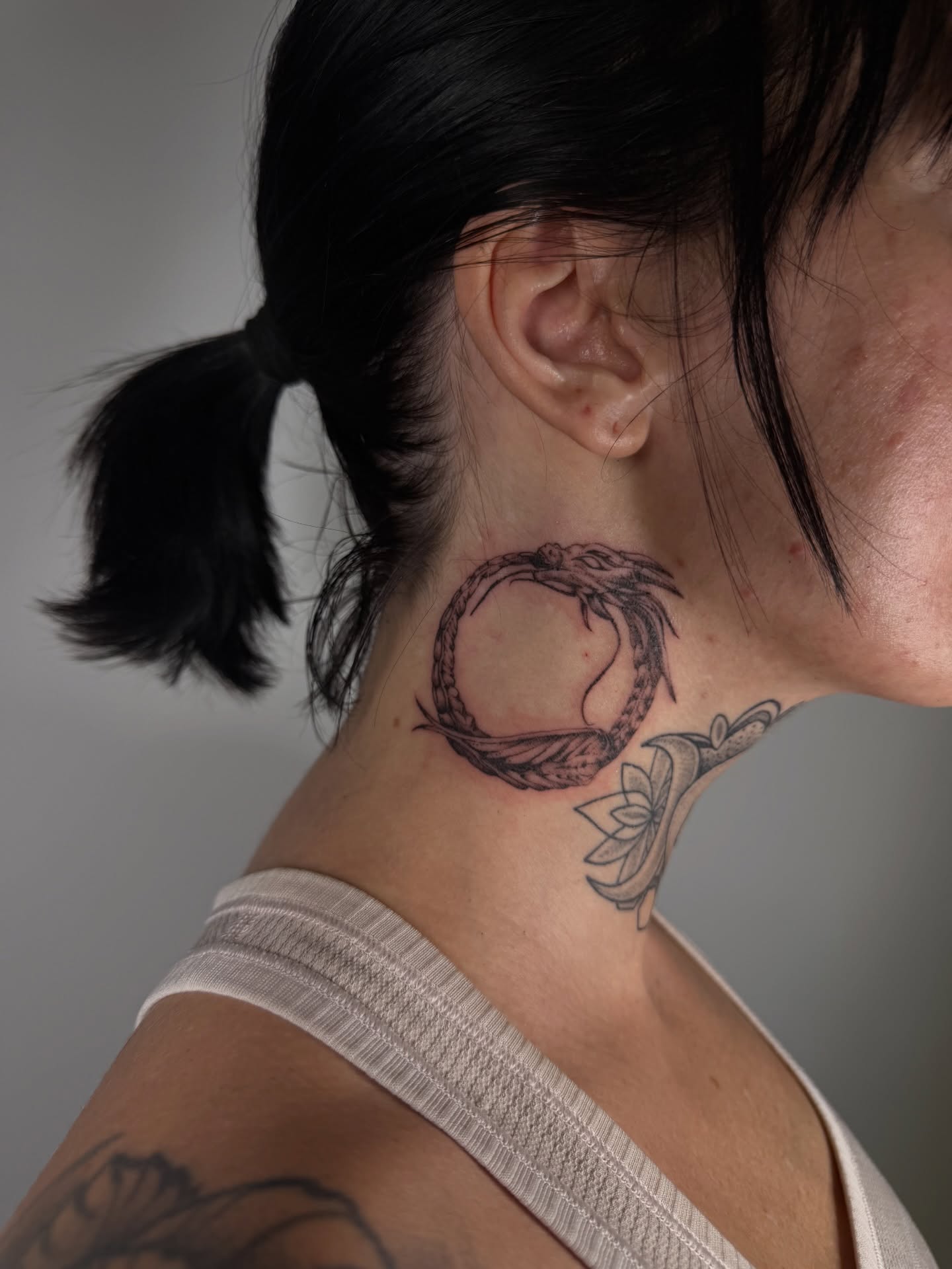 Circle with dragon black and grey tattoo on the neck by Lauren ๐