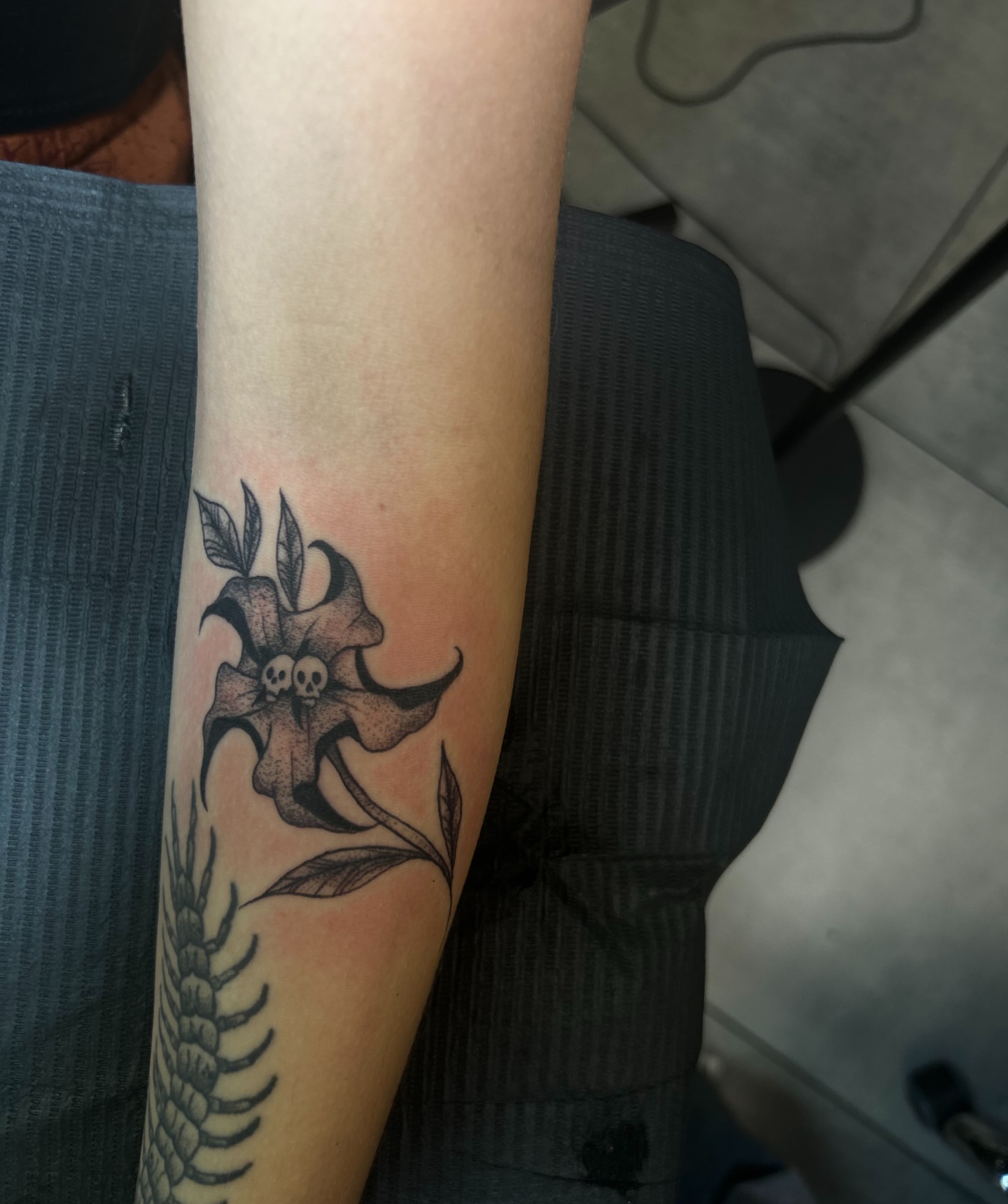 Lily with skulls black and grey tattoo on the forearm by Torrey, Austin, Texas