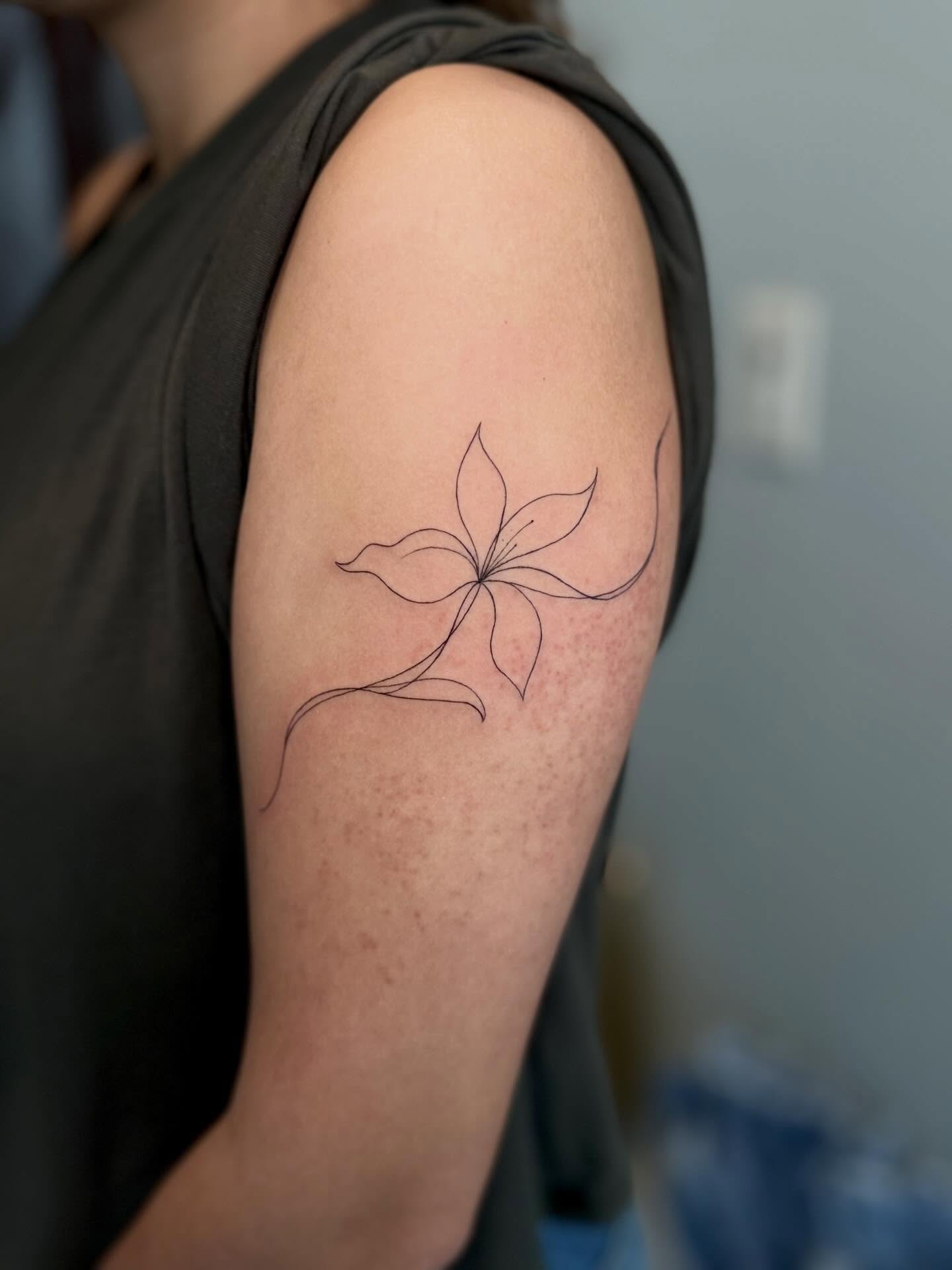 Flower fine line tattoo on the upper arm by Ana Blatt