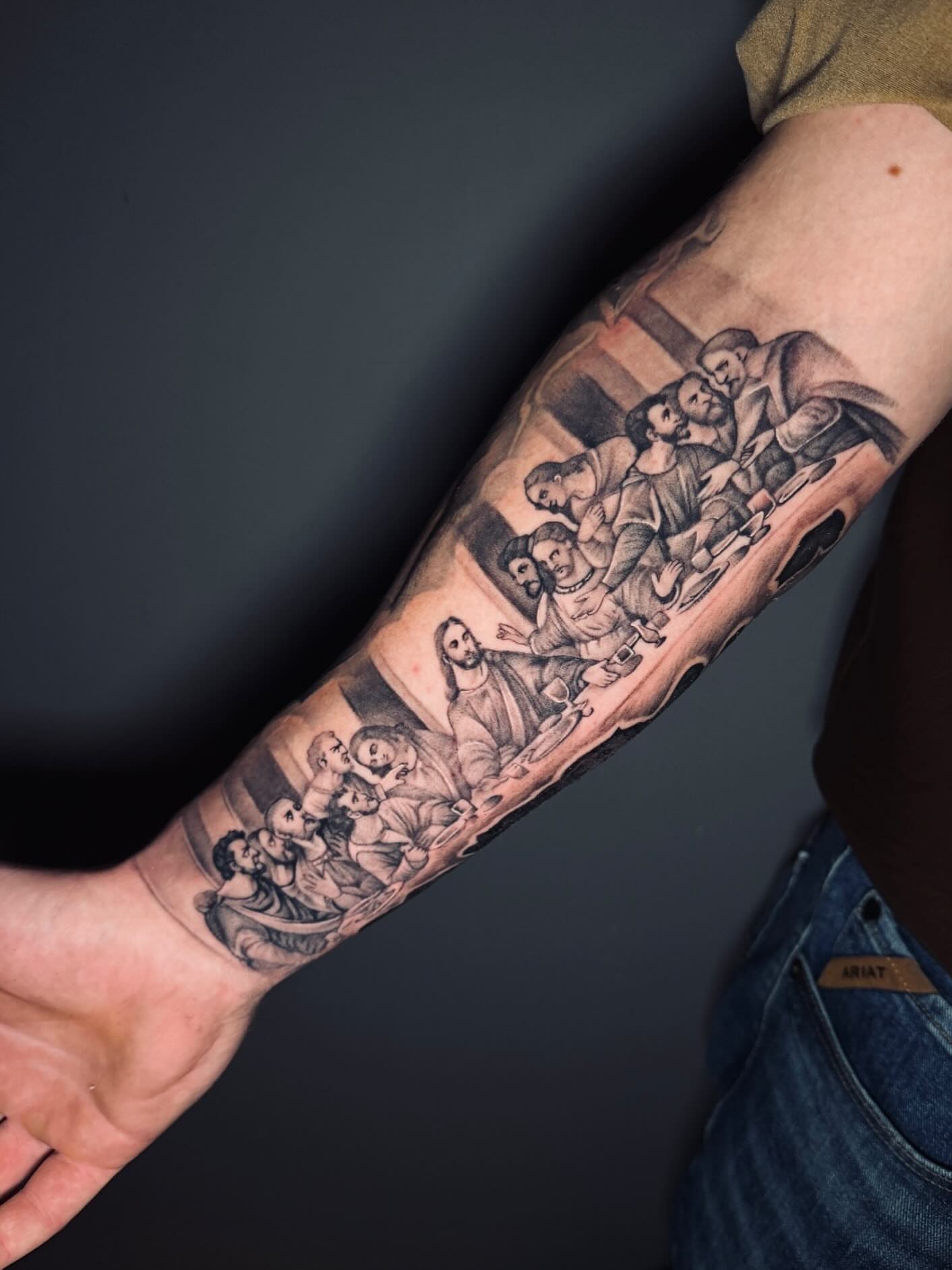 Last supper black and grey tattoo on the forearm by Taylor Steckman