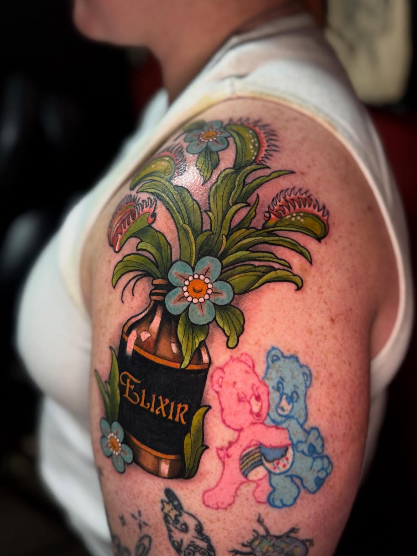 Botanical bottle with flowers American traditional tattoo on the shoulder by Penny - Tattooer