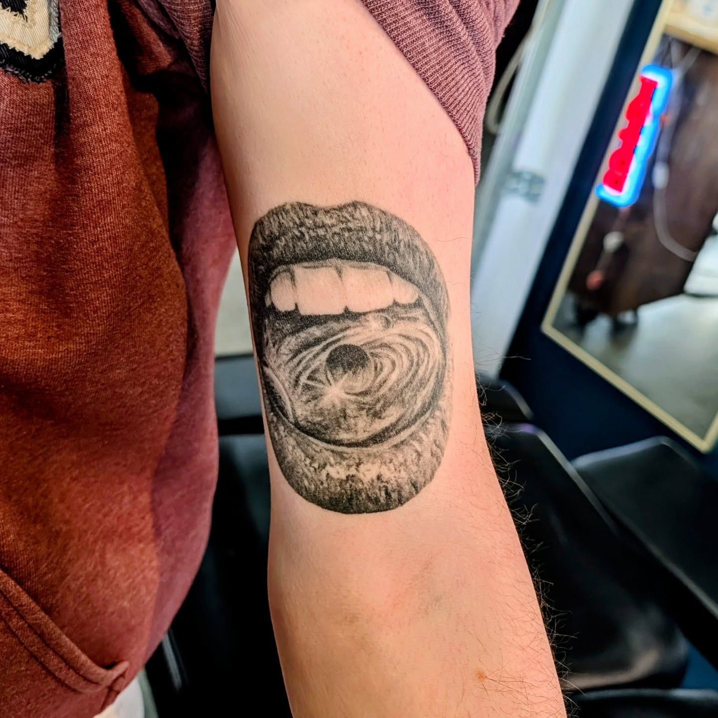 Mouth with swirling vortex realism tattoo on the forearm by Drew King