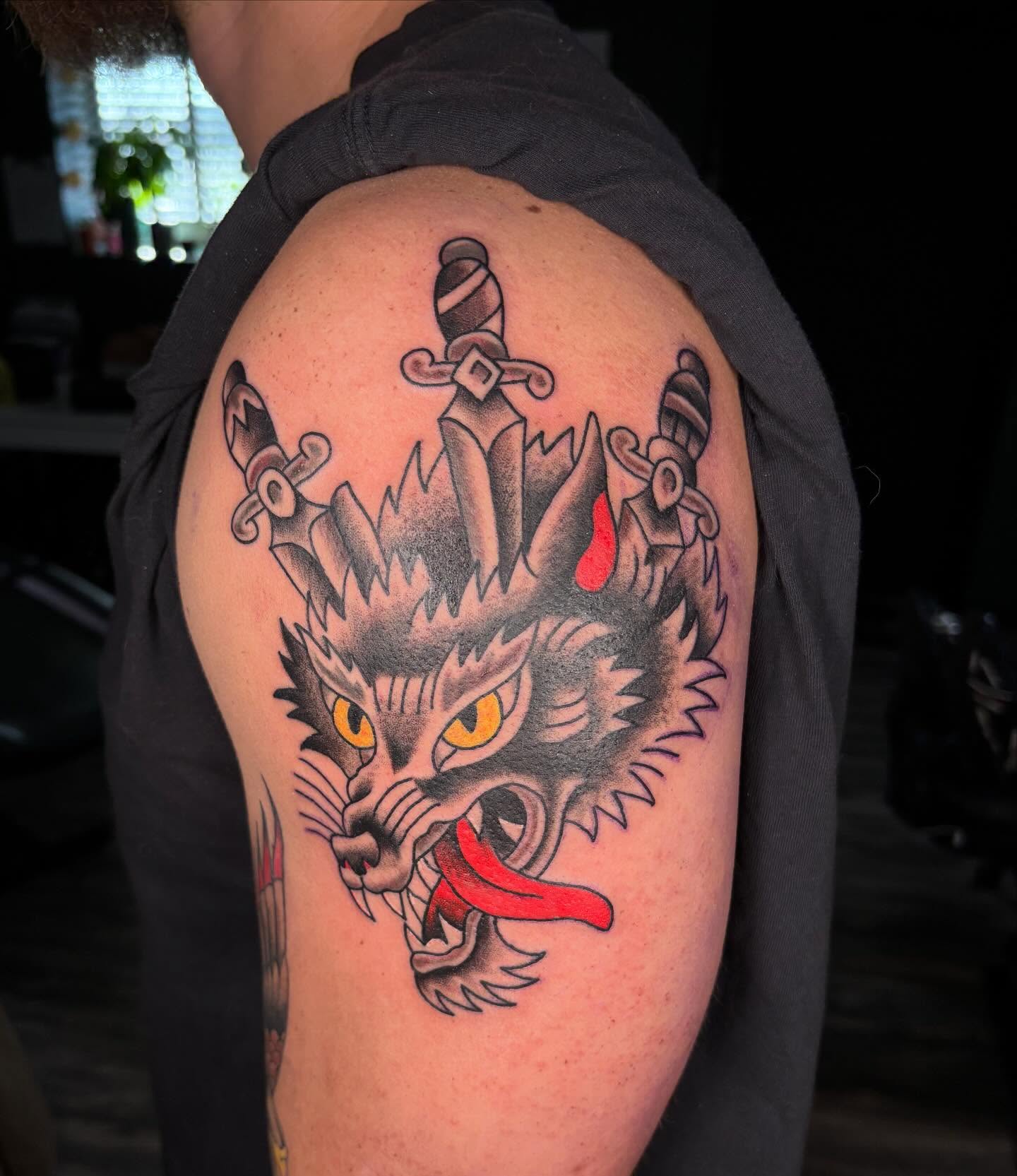 Wolf head with swords American traditional tattoo on the shoulder by @seibastattoos, Virginia Beach, Virginia