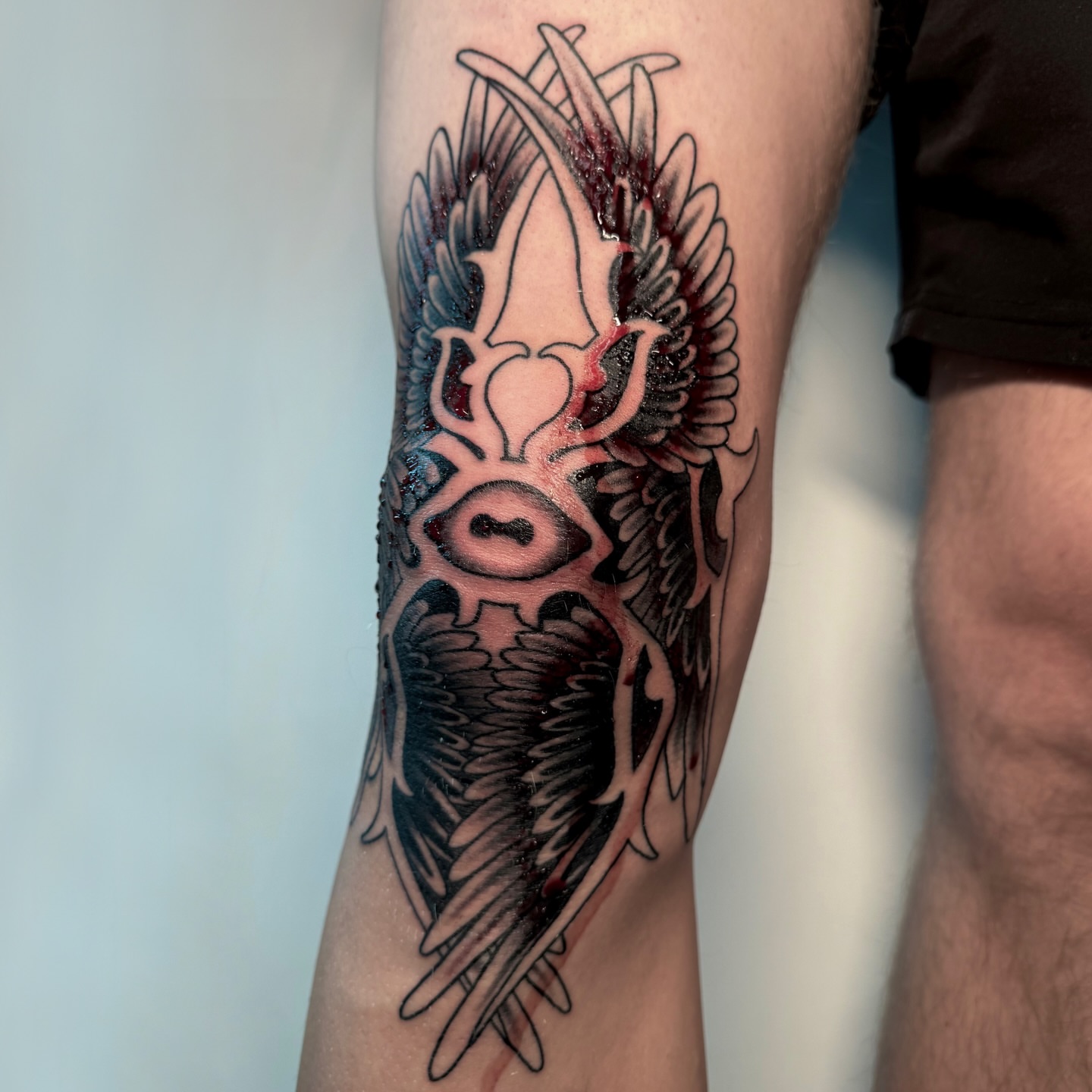 Eye with wings neo-traditional tattoo on the forearm by autumn sky