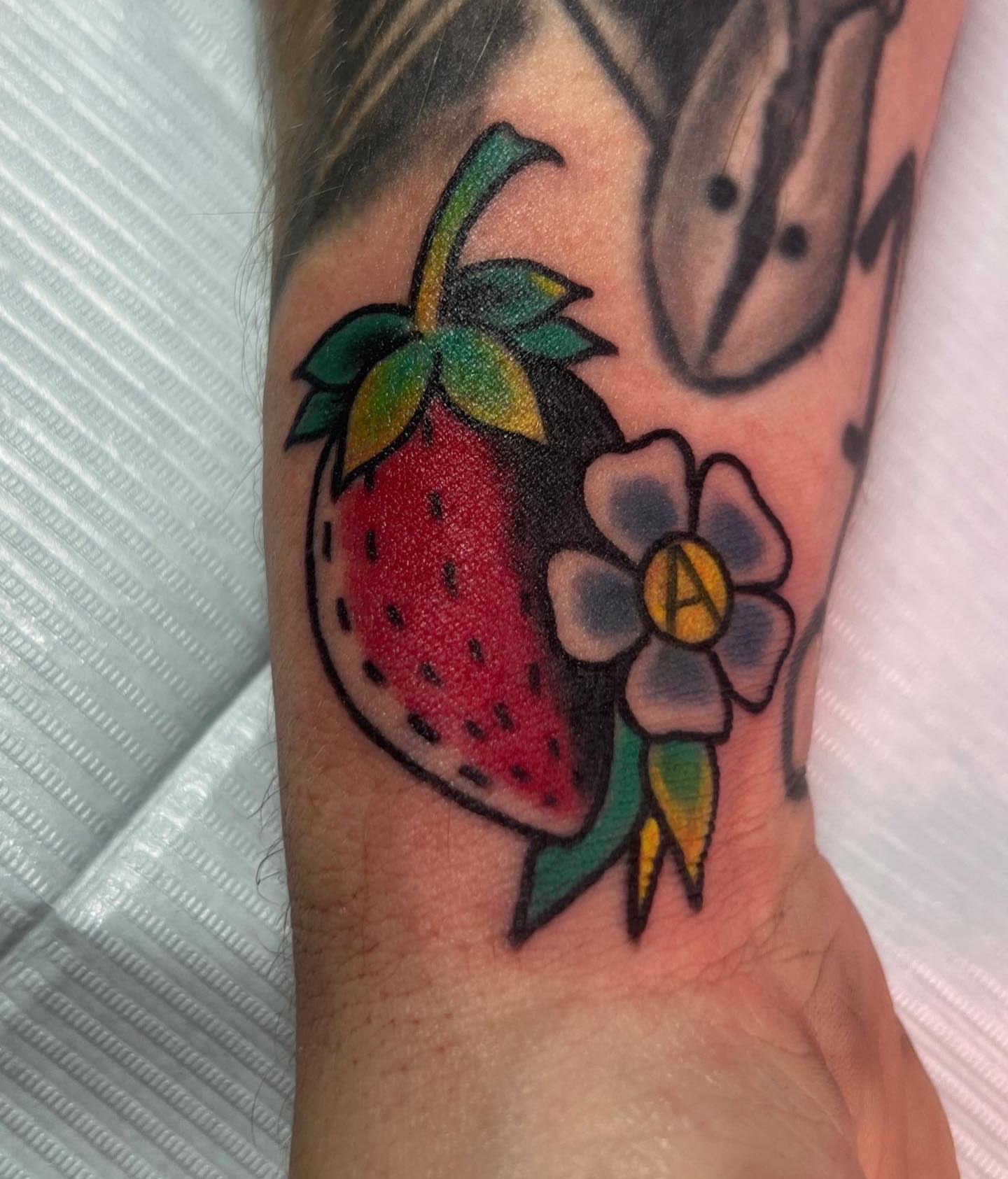 Strawberry and flower American traditional tattoo on the forearm by Steven Blackheart