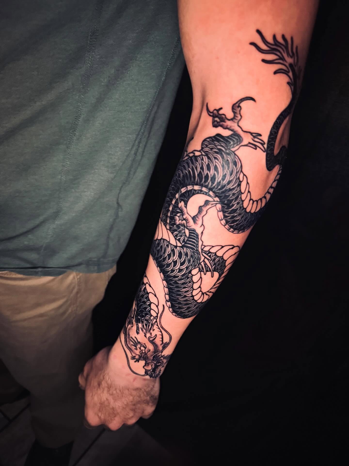 Dragon black and grey tattoo on the forearm by Tattoos By Chico