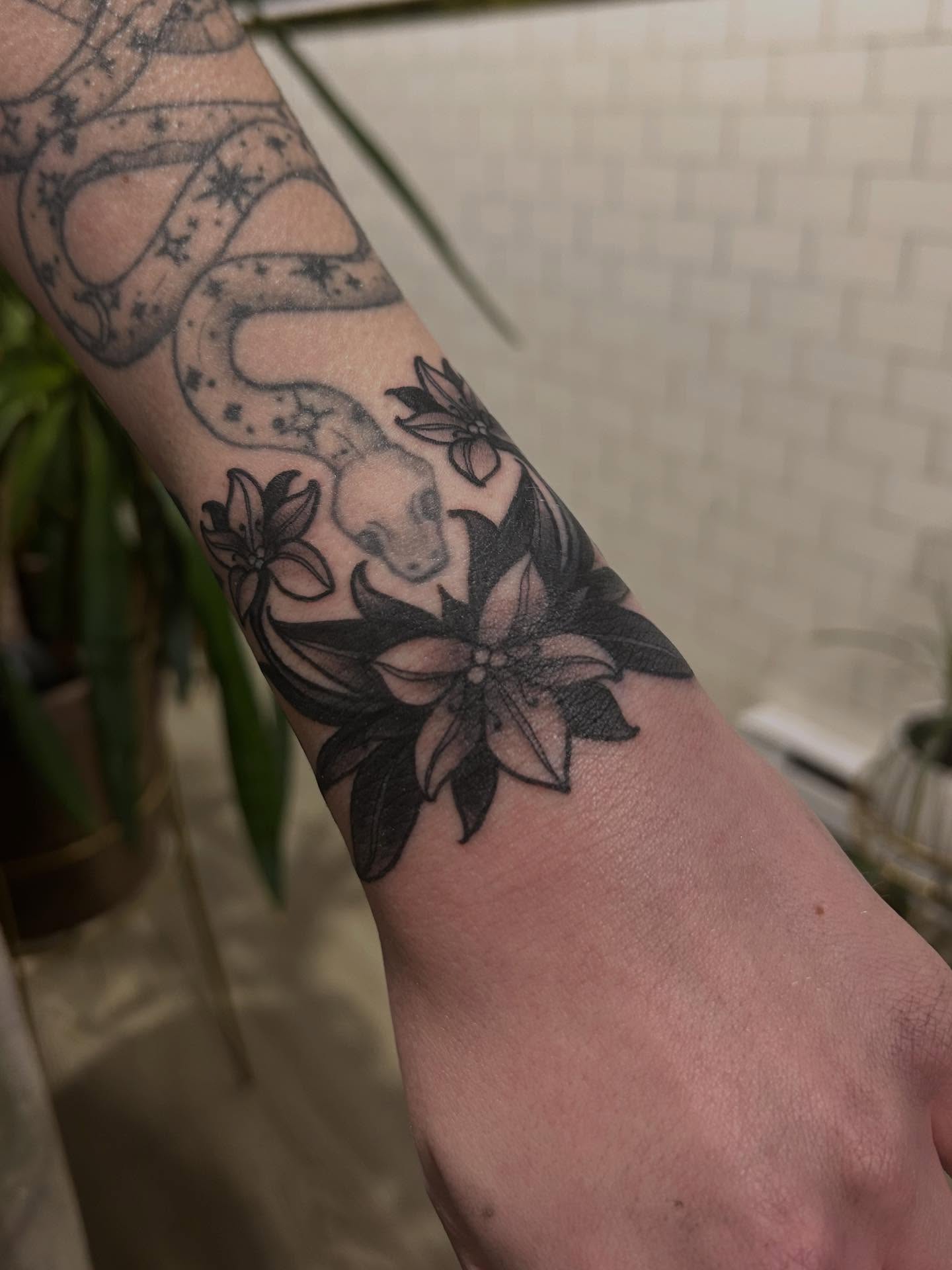 Snake and flowers black and grey tattoo on the forearm by ꧁𝙺𝚊𝚛𝚒𝚗𝚊꧂, Grinnell, Iowa