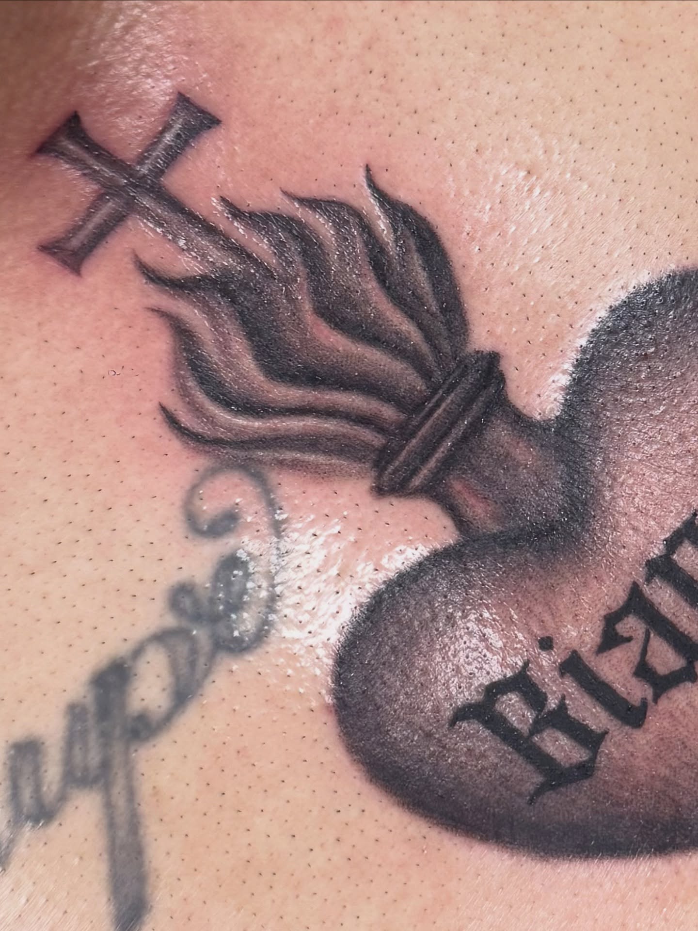 Heart with cross and flames realism tattoo on the chest by Royal Martinez