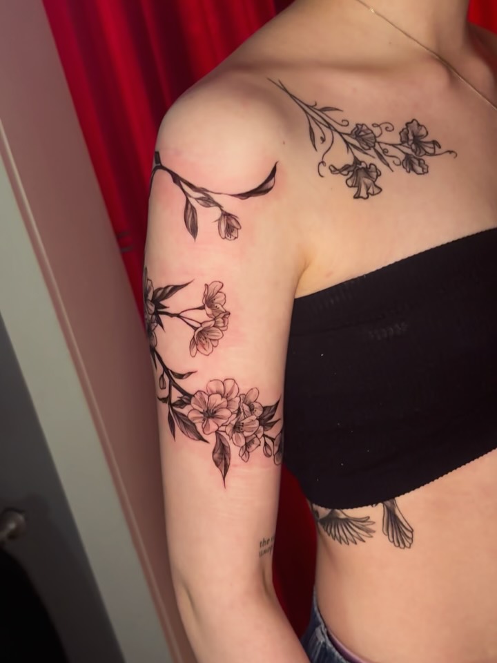 Floral bouquet black and grey tattoo on the upper arm by Kayla