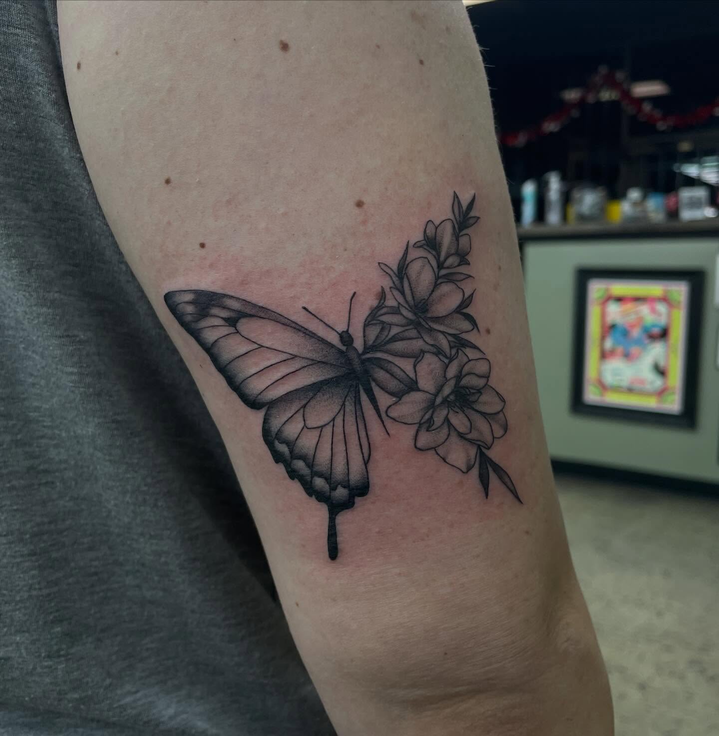 Butterfly and flowers black and grey tattoo on the forearm by kaylee