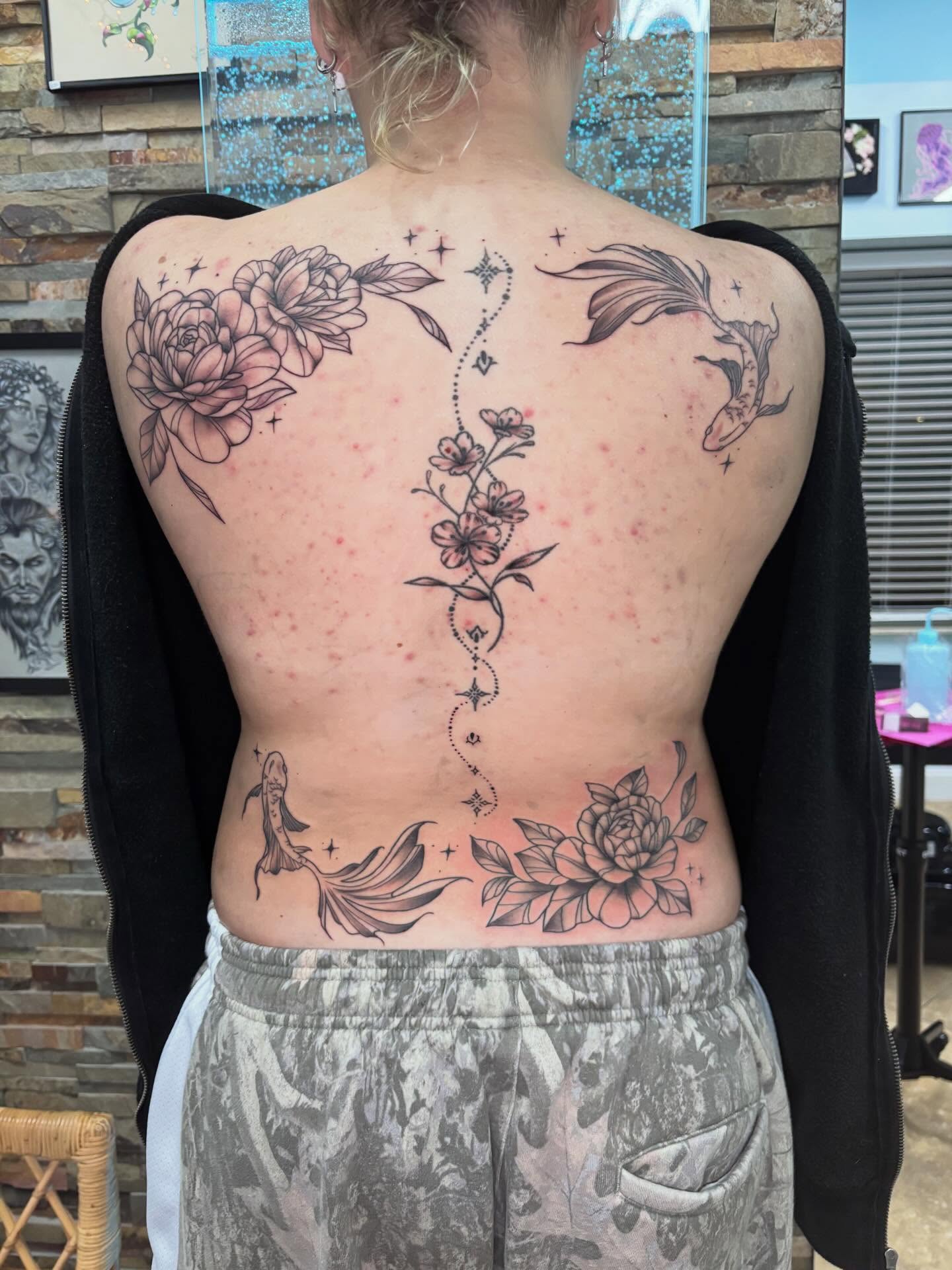 Floral and fish black and grey tattoo on the back by Stephanie Rowe