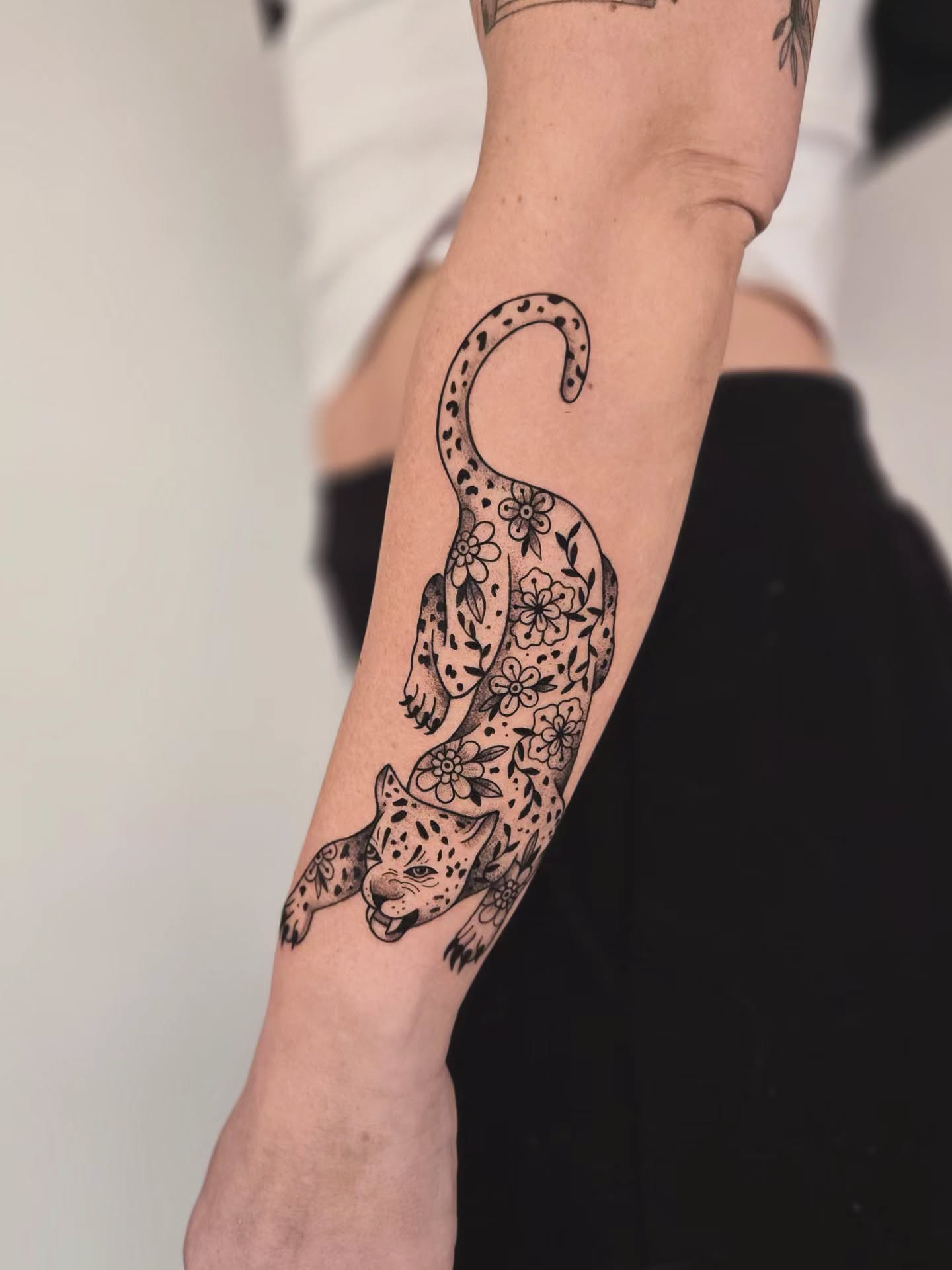 Leopard with floral patterns black and grey tattoo on the forearm by Kirstie Lew Tattoo